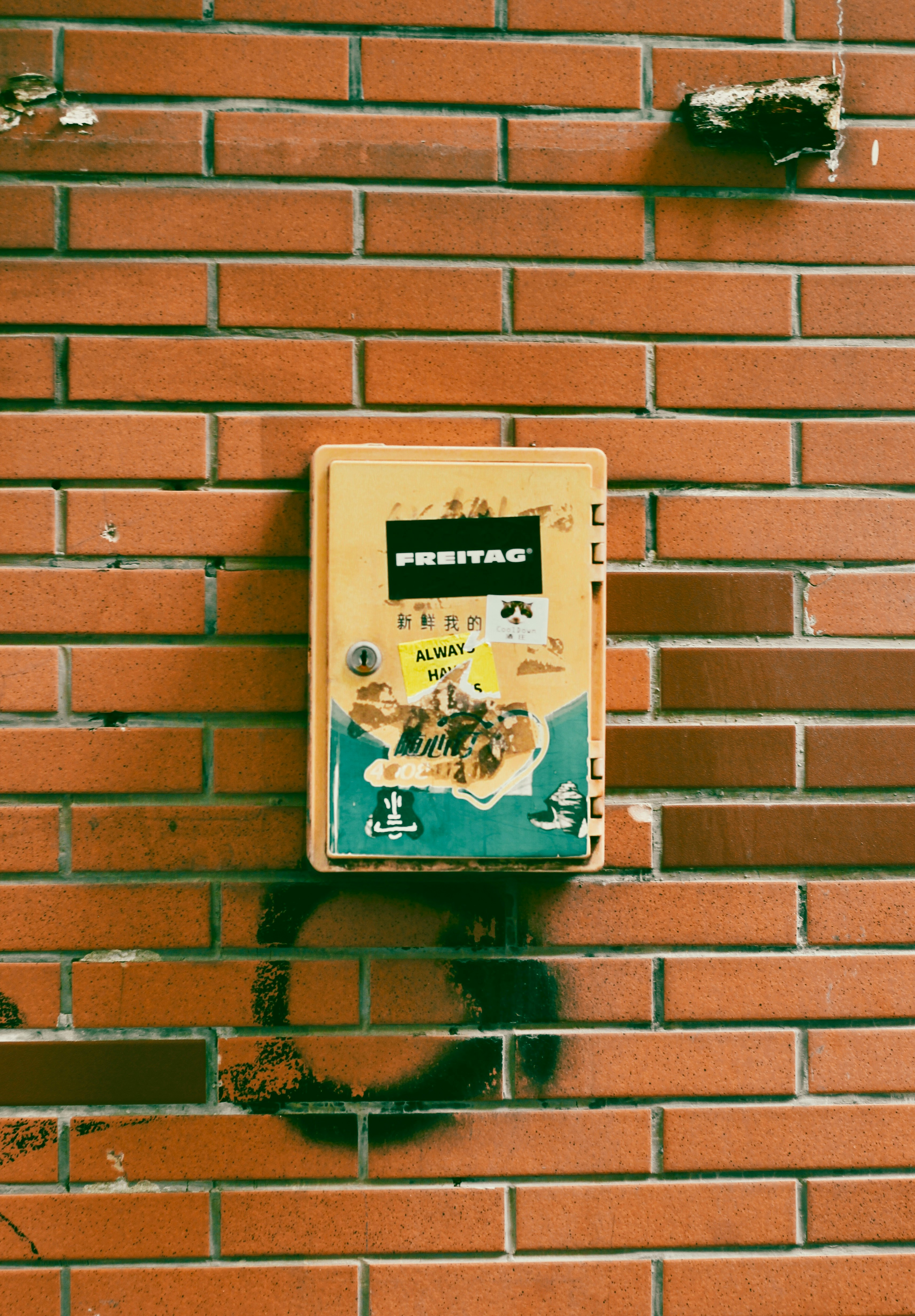 Yellow box with stickers on brick wall