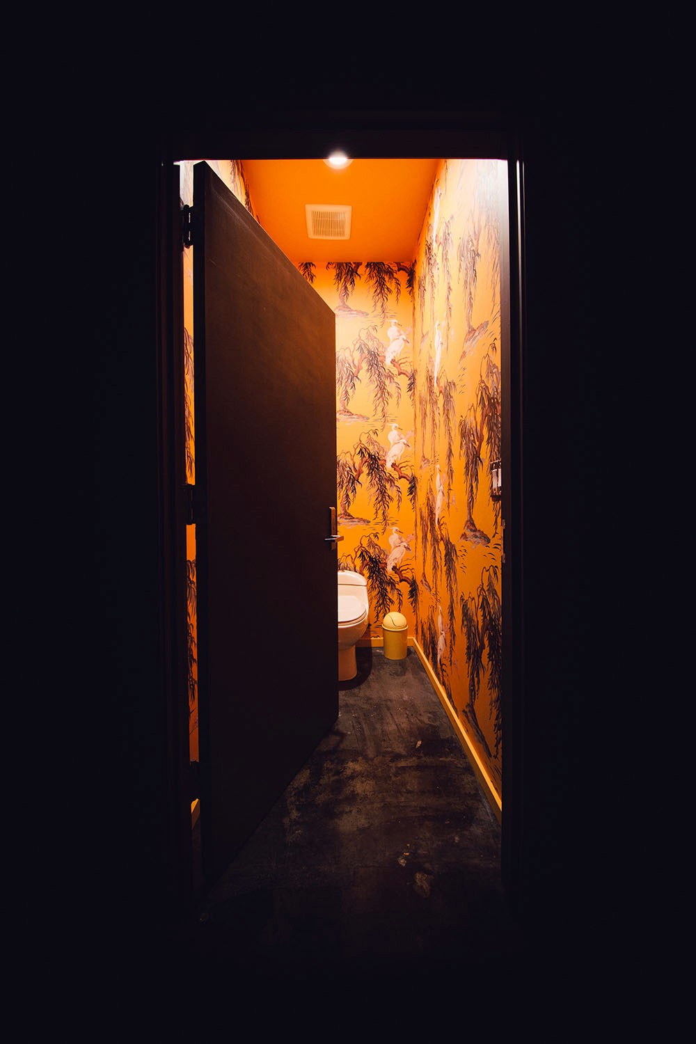 The "Crane" bathroom in the washroom at Particle Studio in Seattle, WA. It features a yellow toilett, crane wall paper in a yellow color and a chandalier made of yellow paper cranes. .