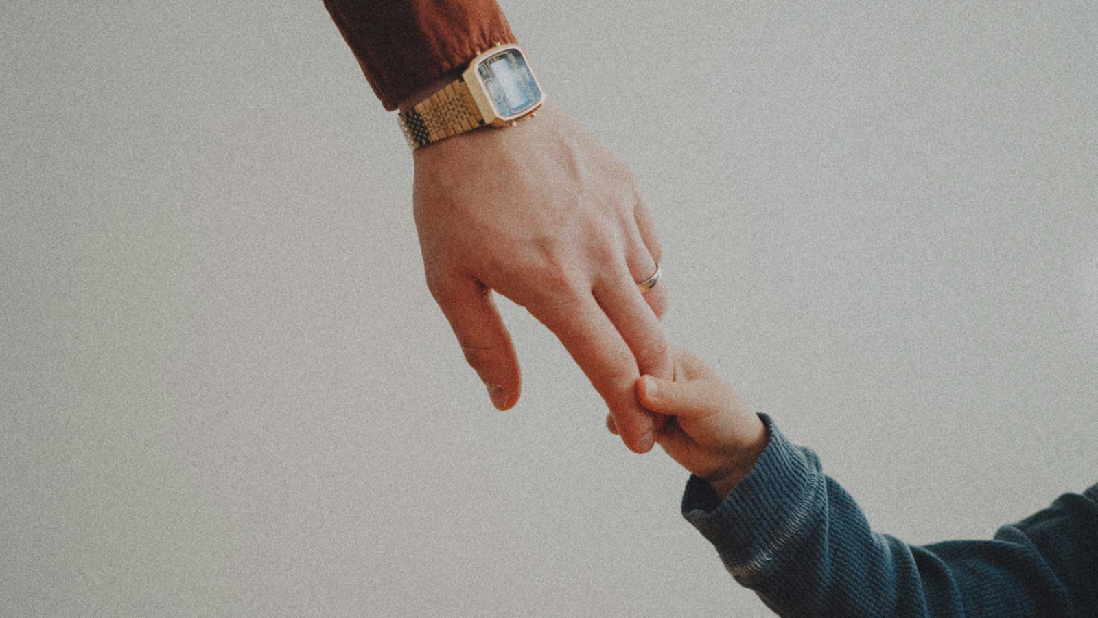 Foto de la mano de un niño sosteniendo la mano de su padfe, en la columna "Reiventar la paternidad" de IdeaPaís.