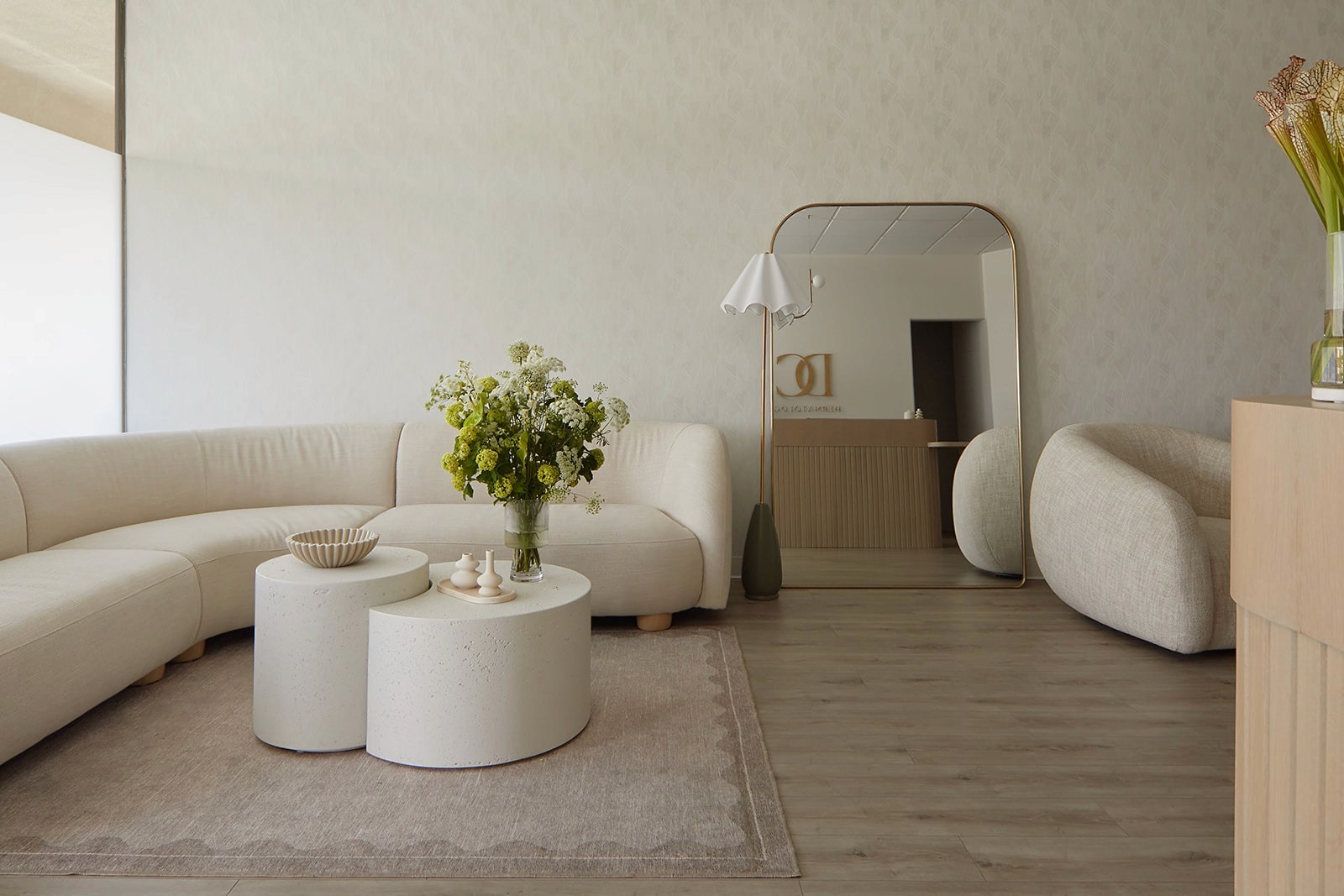 Curved lounge seating in the DC Dermatology waiting area, reflected through a brass-framed mirror with the reception desk visible beyond.
