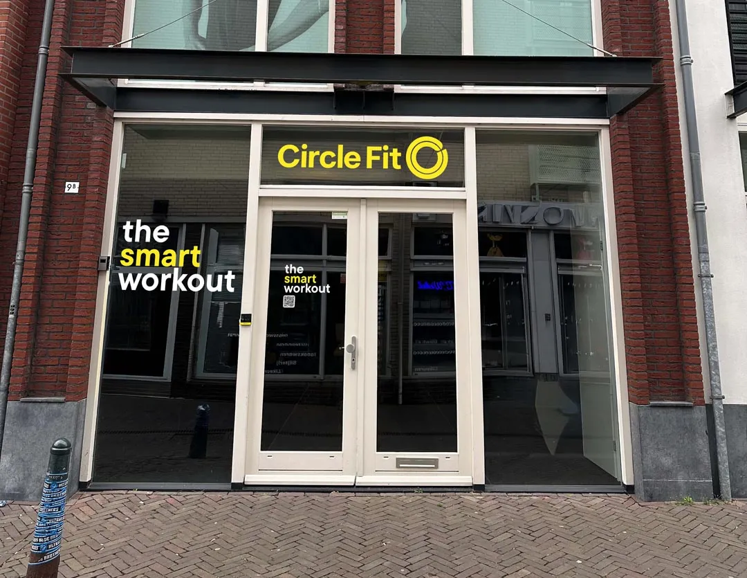 A Circle Fit hub with large glass windows and a yellow sign, displaying the entrance and business name prominently.