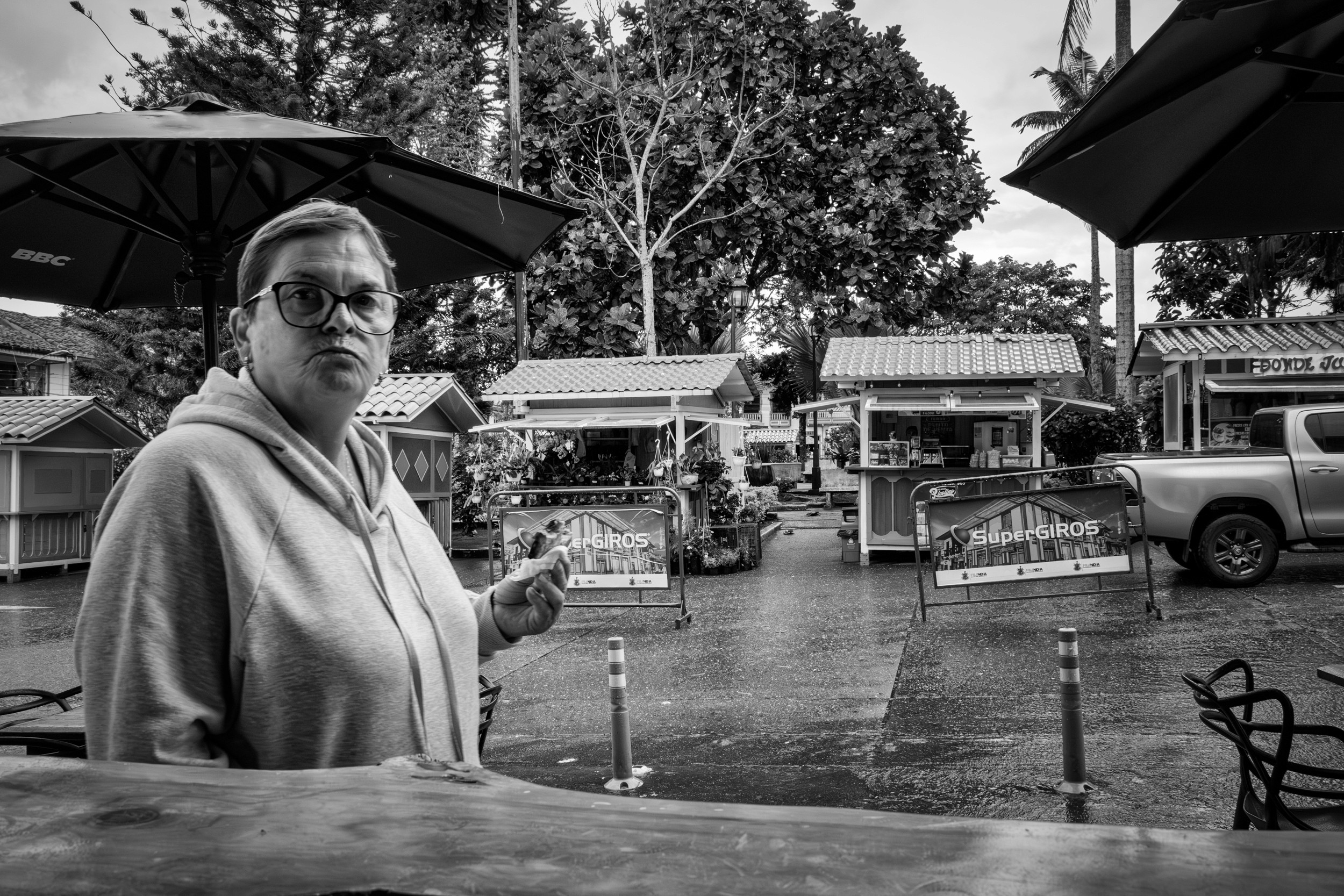 Rainy street scene with people passing by a bar window.
