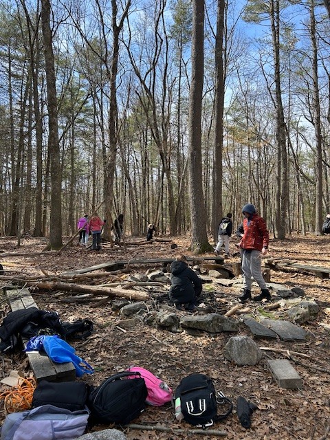 Students building a shelter from branches during an outdoor program