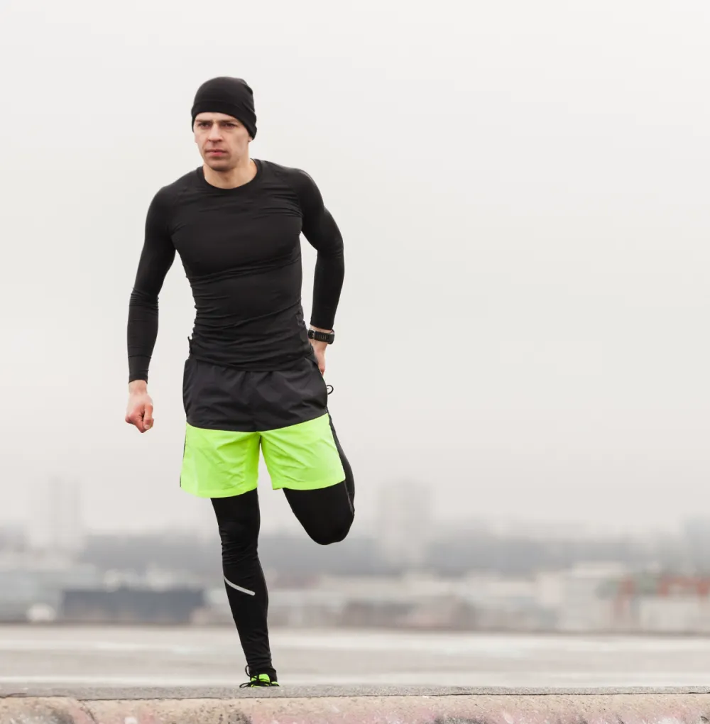 A man dressed in black and yellow is sprinting on a concrete surface, showcasing athleticism and determination.