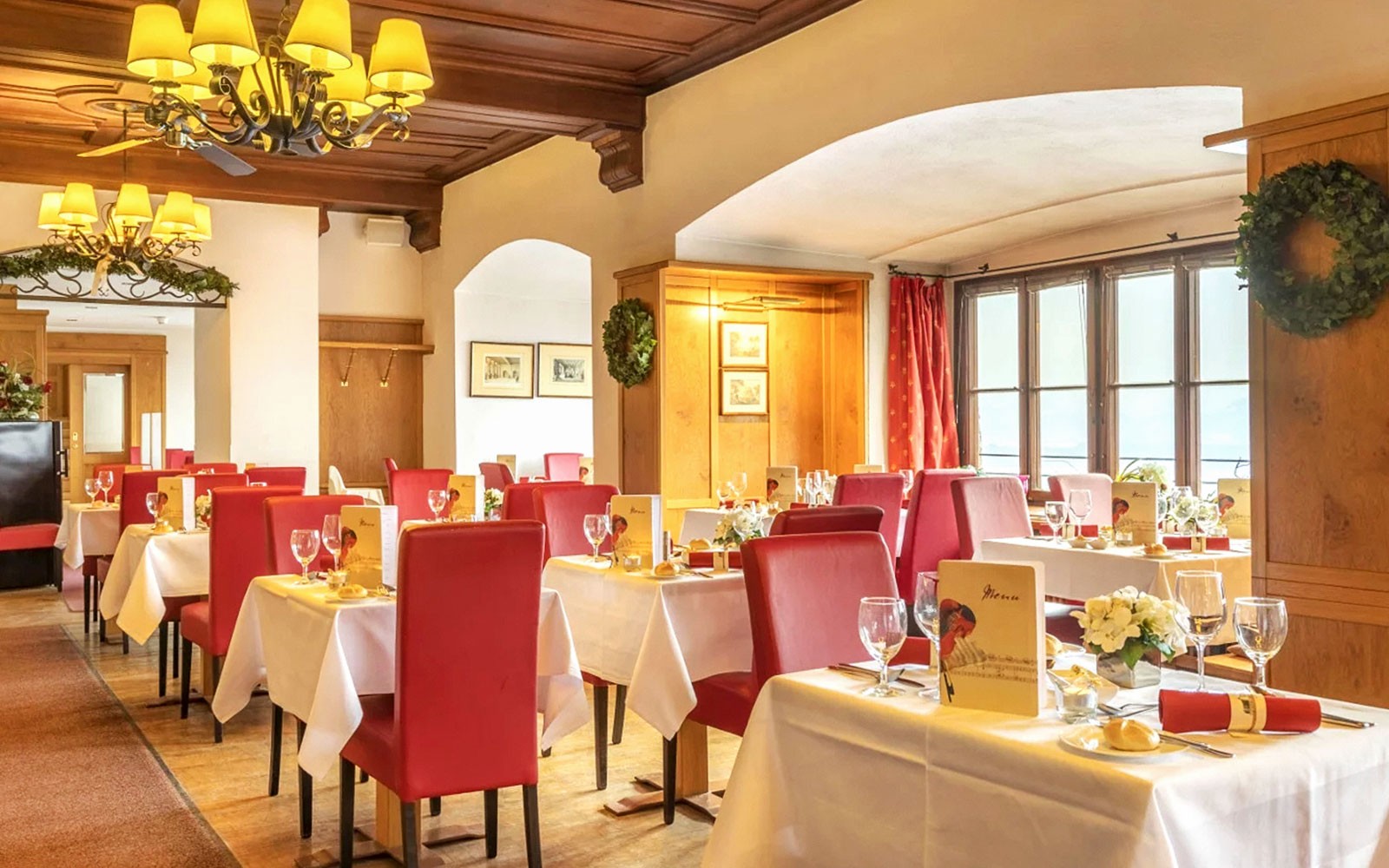 Dinner setup in Fortress Hohensalzburg dining room with red chairs and white tablecloths.