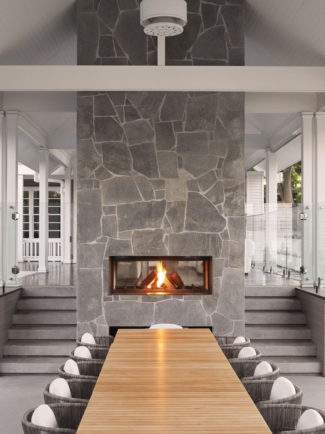 indoor-outdoor dining area with stone fireplace and central timber table
