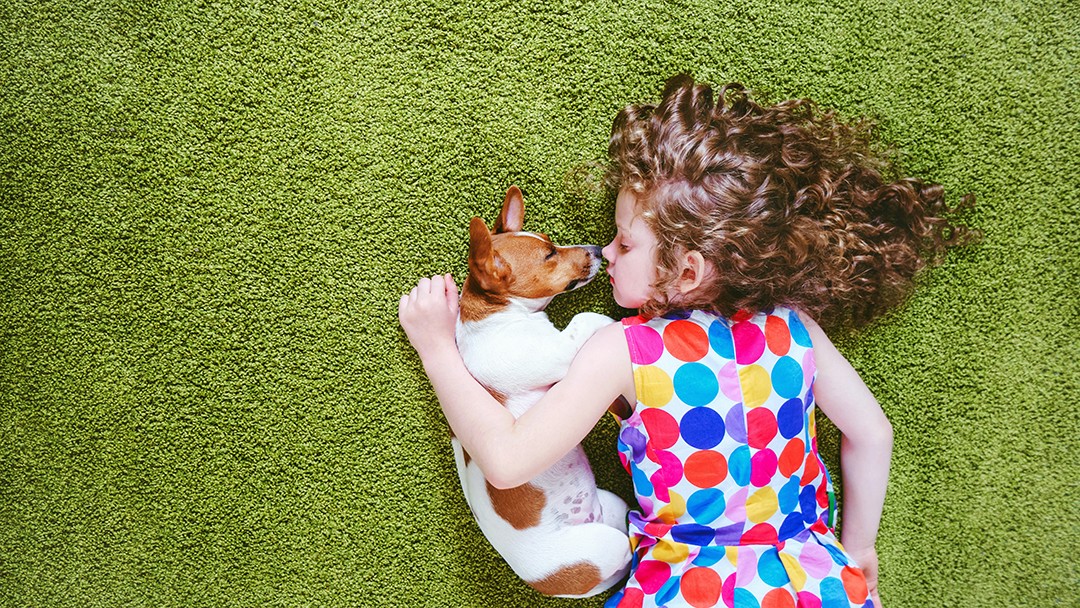 girl laying on grass with dog
