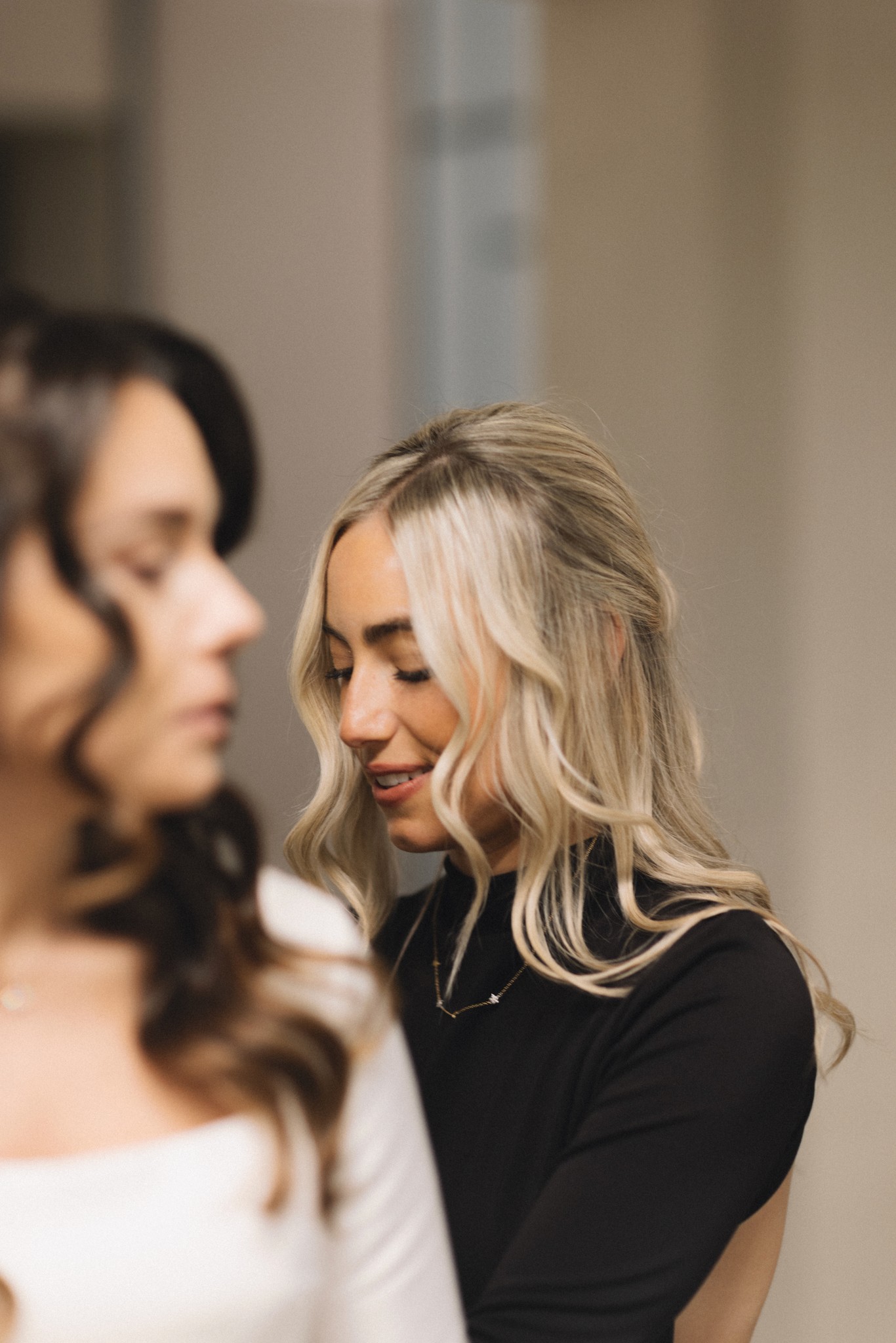 Sposa bionda sorride mentre un'amica sistema i dettagli del suo look prima della cerimonia al Circolo di Lettura a Parma