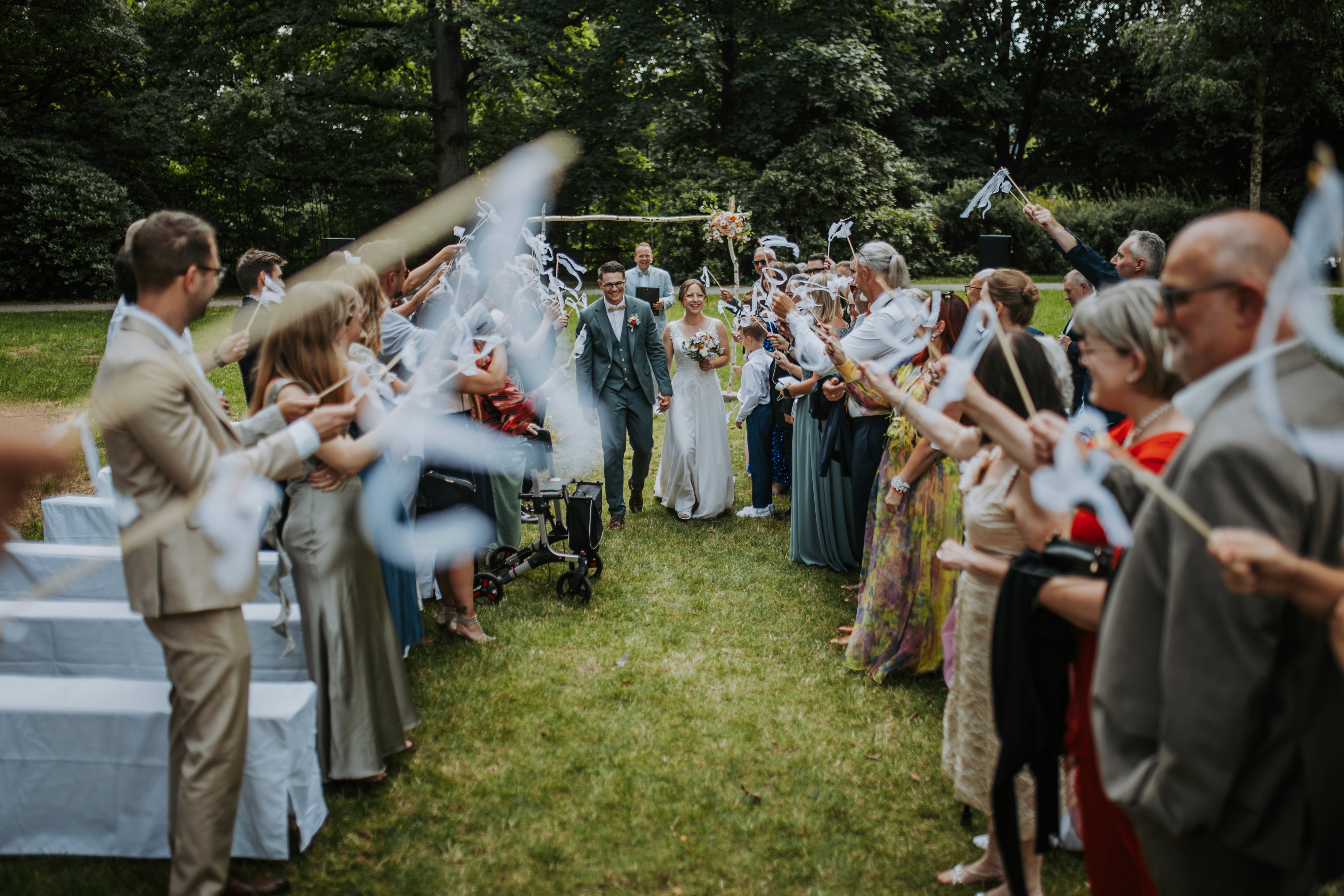 Braut in detailreichem weißem Kleid und Schleier steht im Freien.