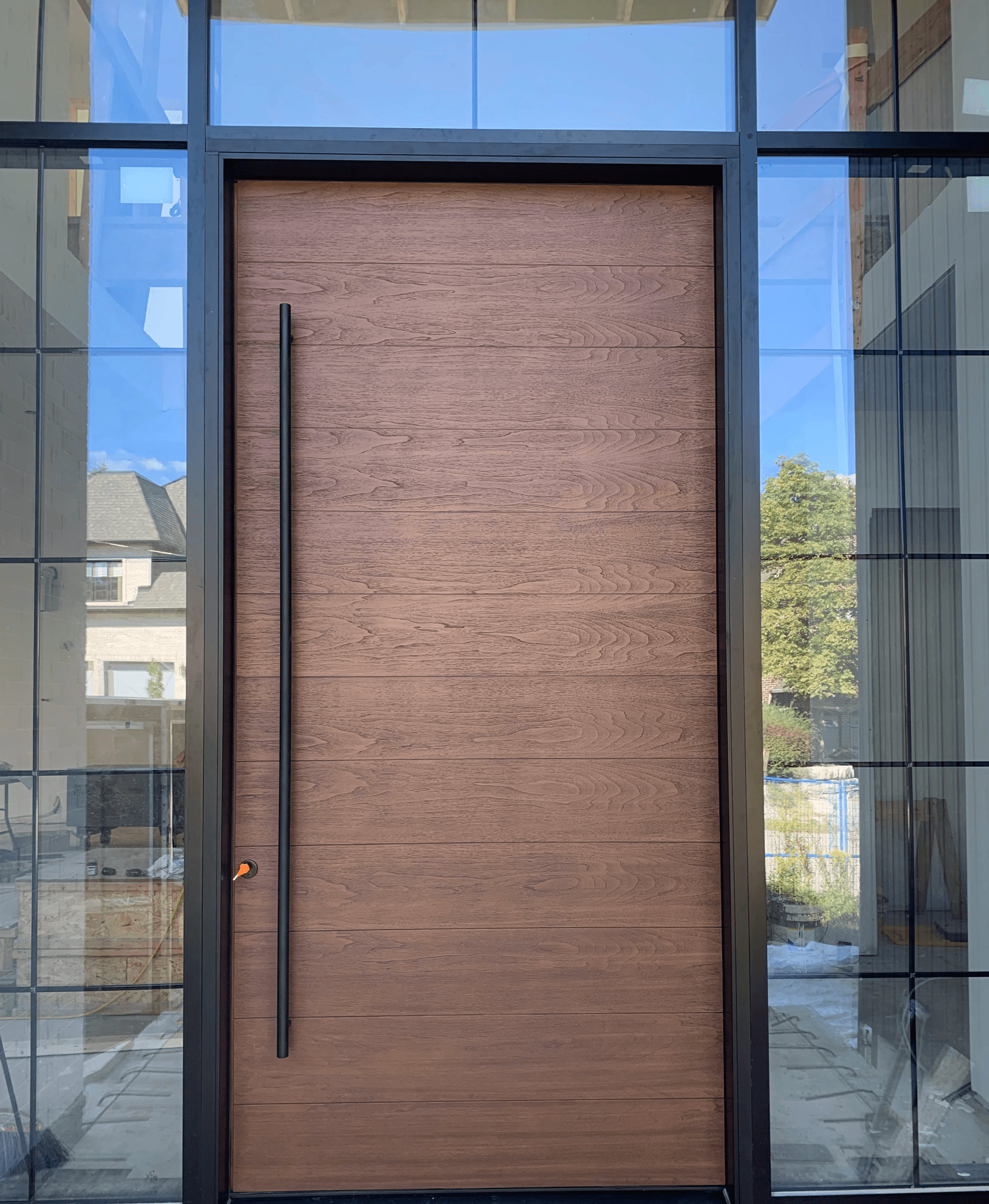 Minimalist fiberglass front door in a dark charcoal finish for a modern home exterior.
