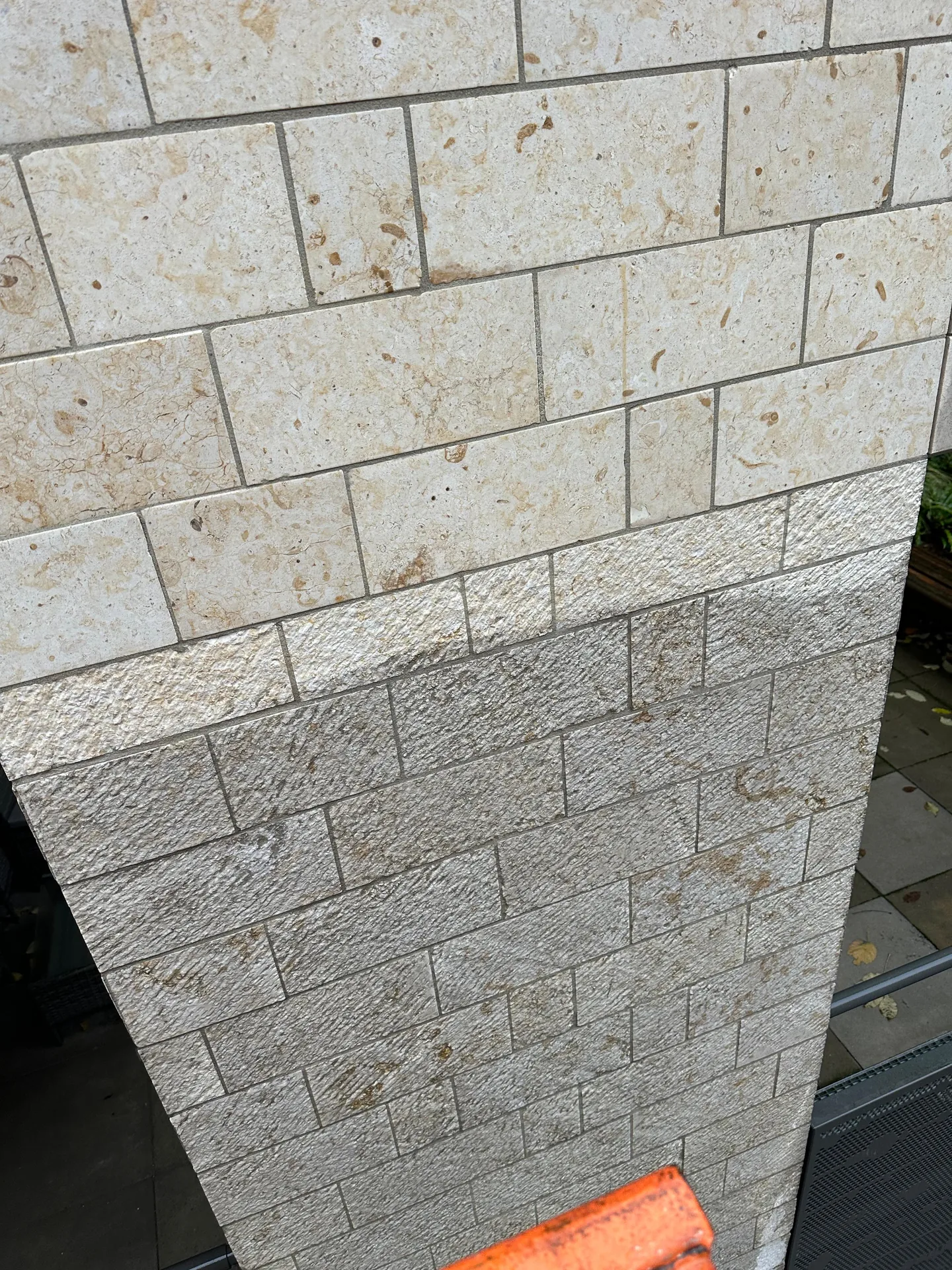 Natuurstenen gevel na reiniging, met het gereinigde lichte deel naast het nog vervuilde donkere deel