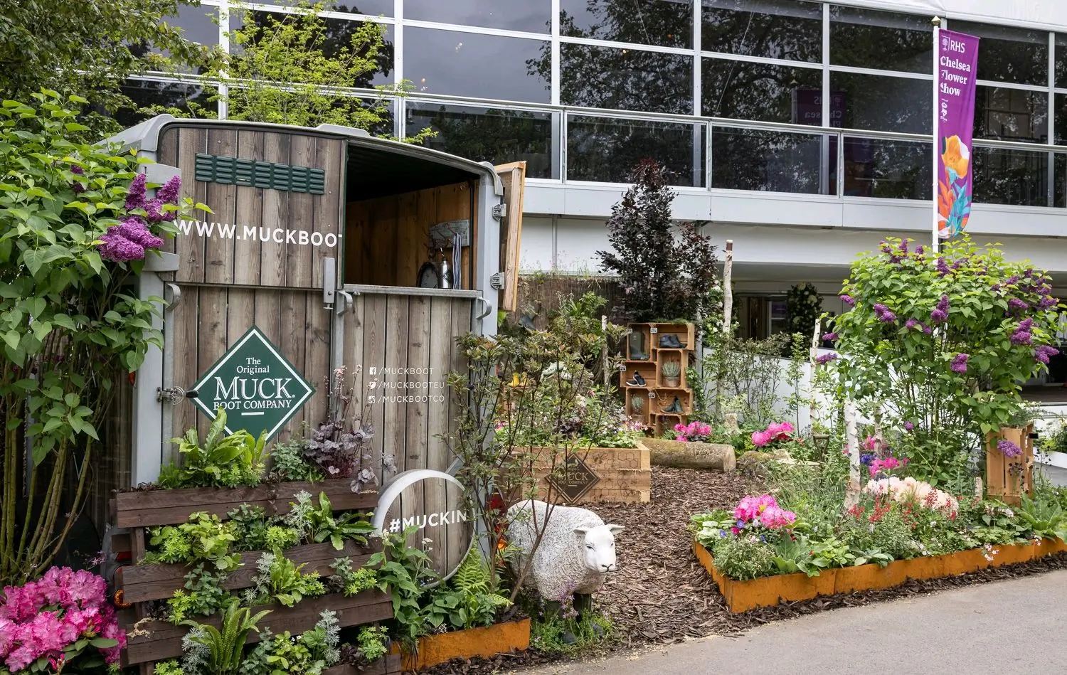 A vibrant garden with colorful flowers and plants, adjacent to a modern building with large windows.