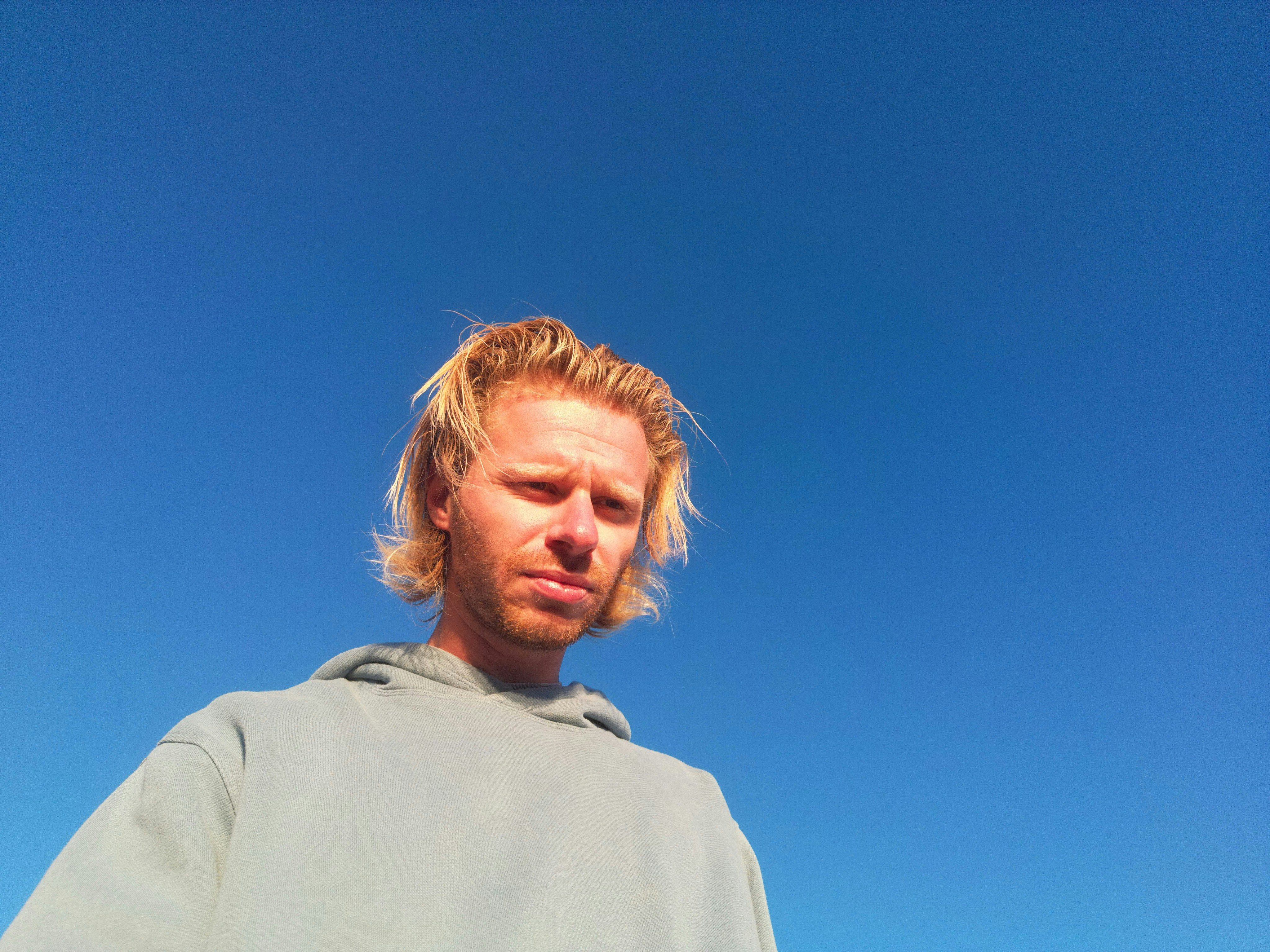 Man with blond hair against a blue sky