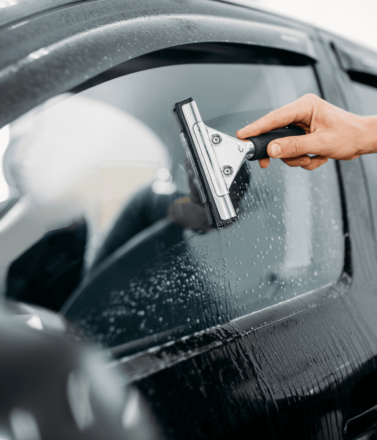 Hand cleaning car window with squeegee