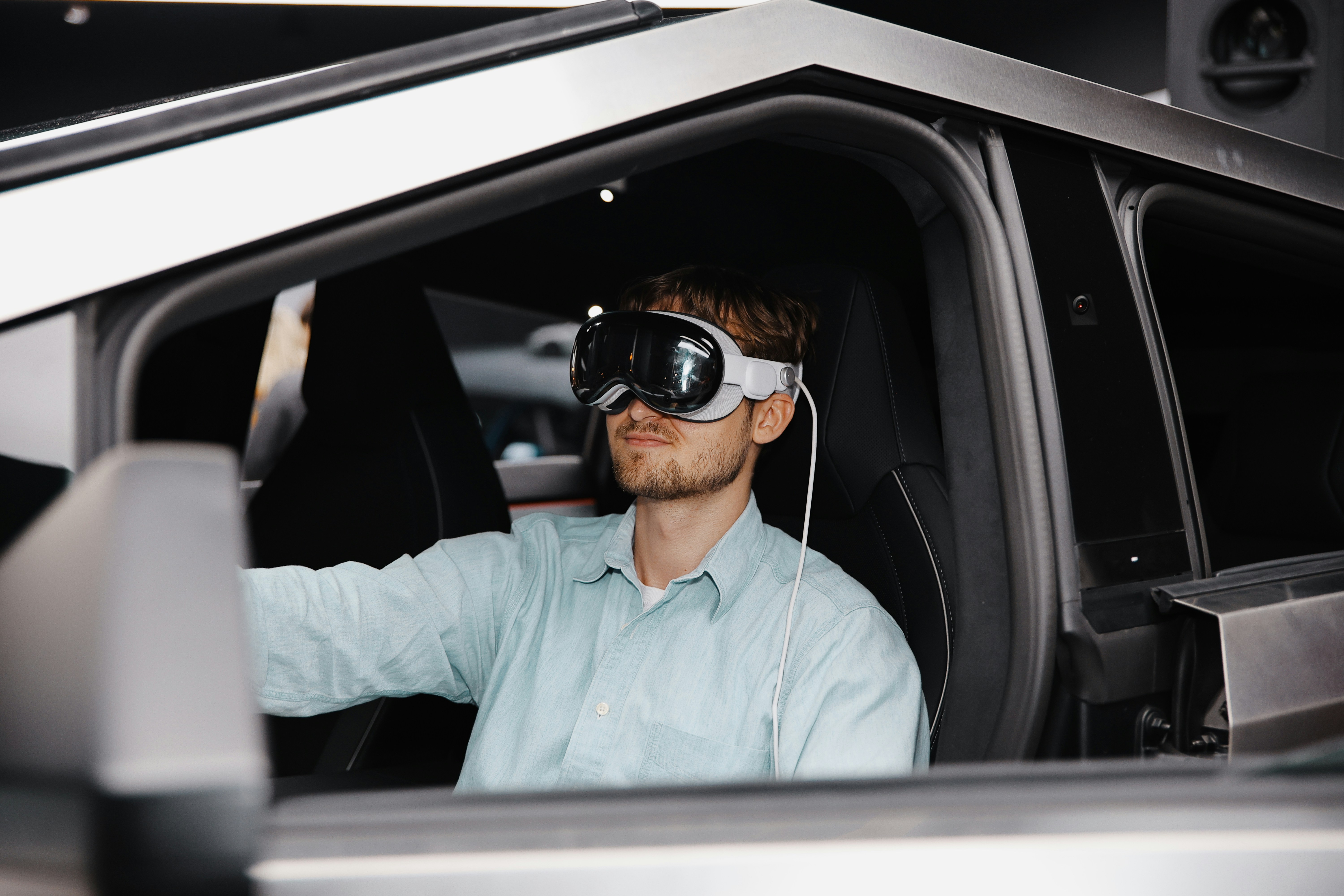 a man sitting in a Tesla Cybertruck driver's seat wearing a virtual reality (VR) headset