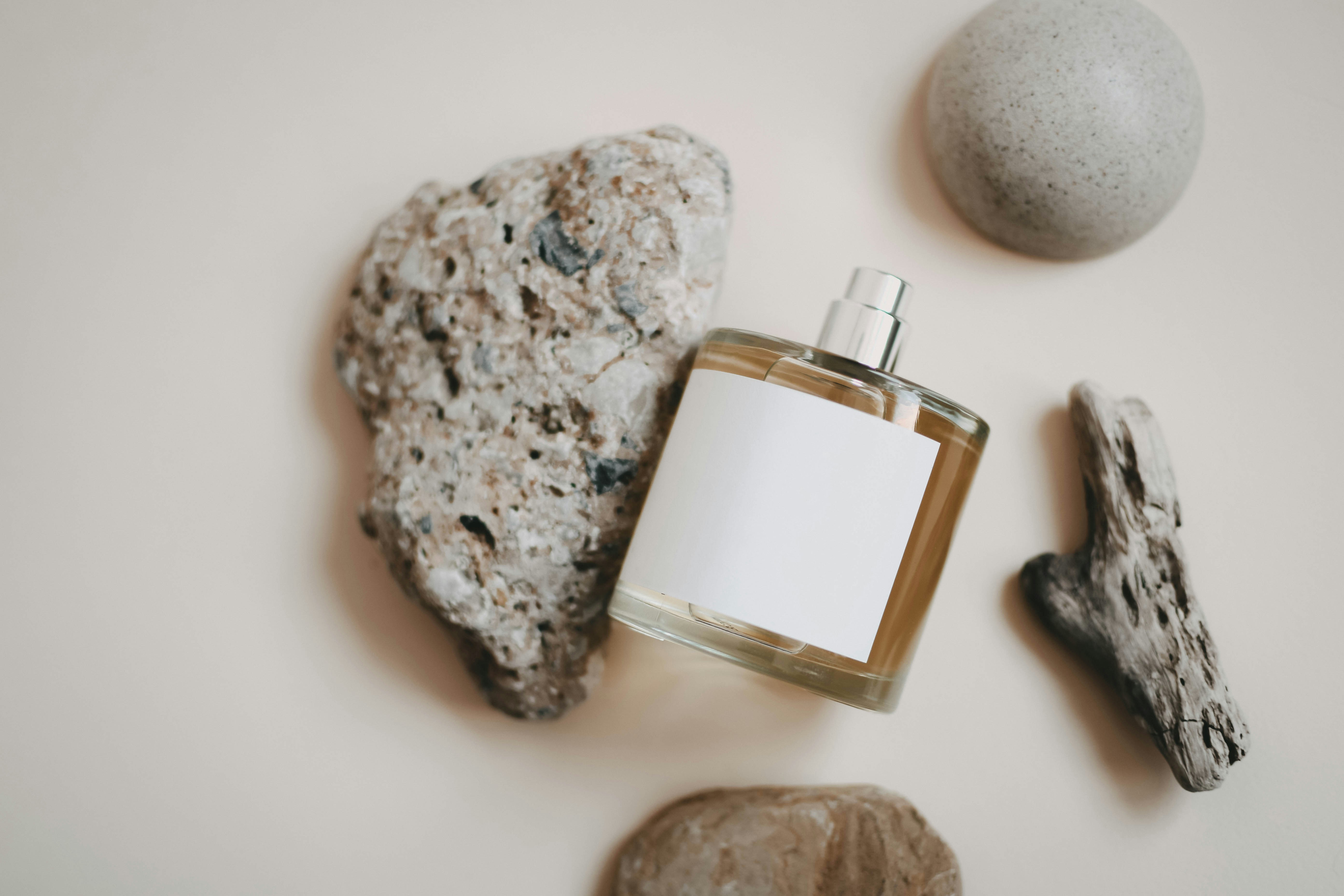 a bottle of cologne next to rocks and a rock