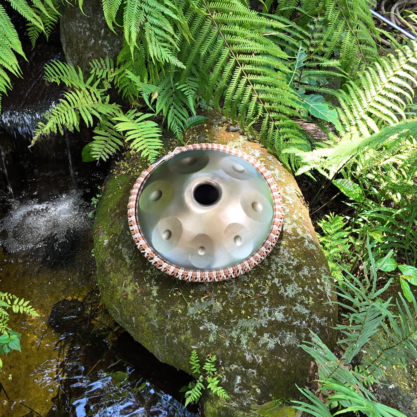 A mini stainless steel handpan on a rock