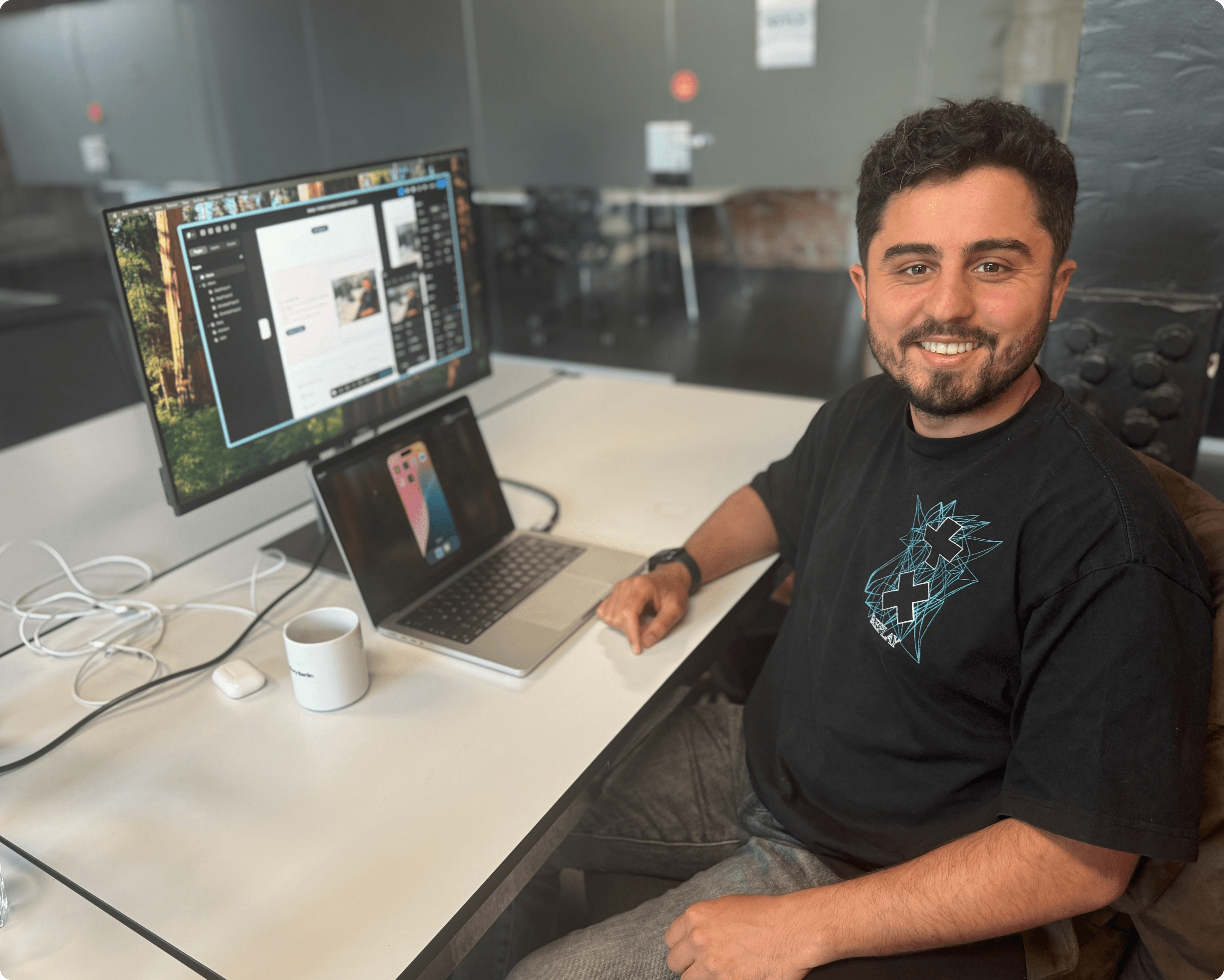 Professional photo of Khalit Hartmann in his office, smiling at the camera while seated in front of his laptop. Modern workspace setting, business casual attire, and confident expression.