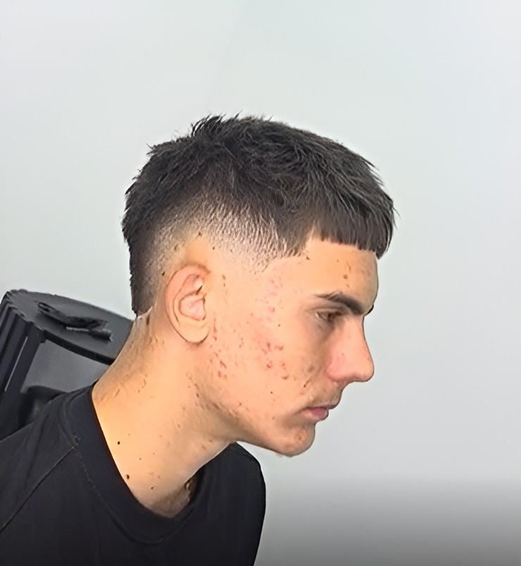 Barber holding clippers and comb near a man's hair