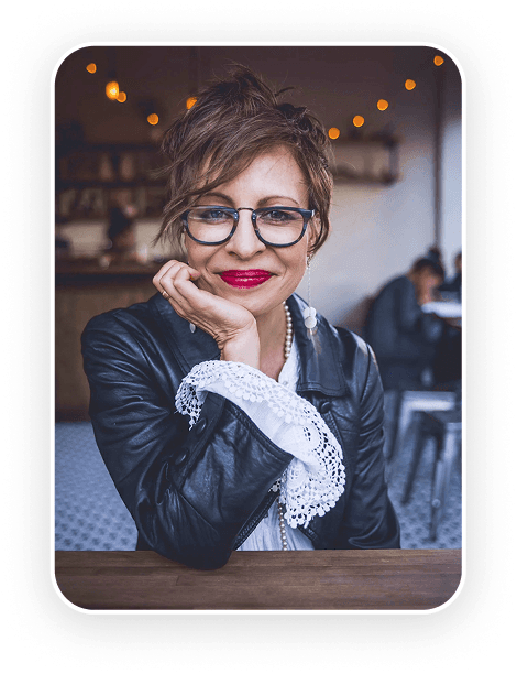 Megan Sheerin with a confident expression rests her chin on her hand, wearing stylish attire.
