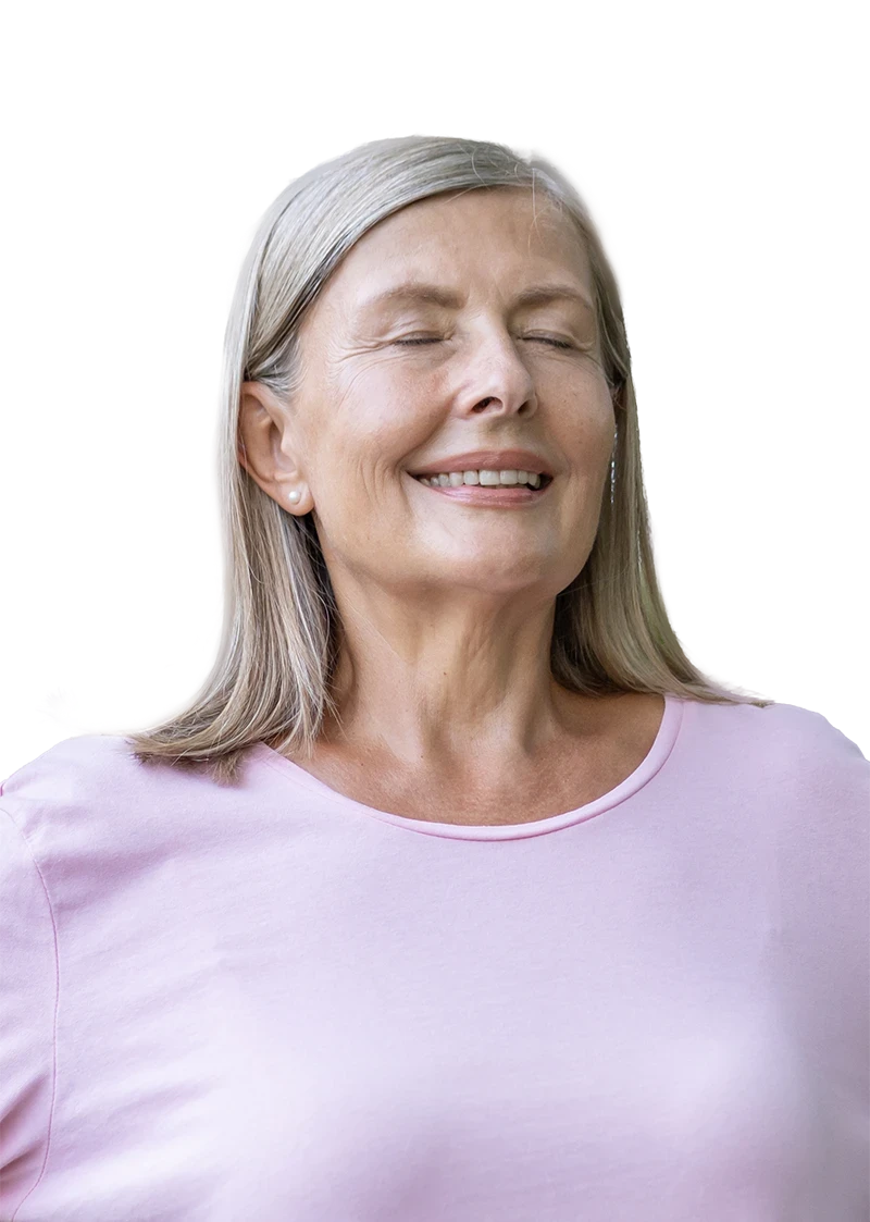 Smiling older woman looking relaxed against a neutral background breathing in.