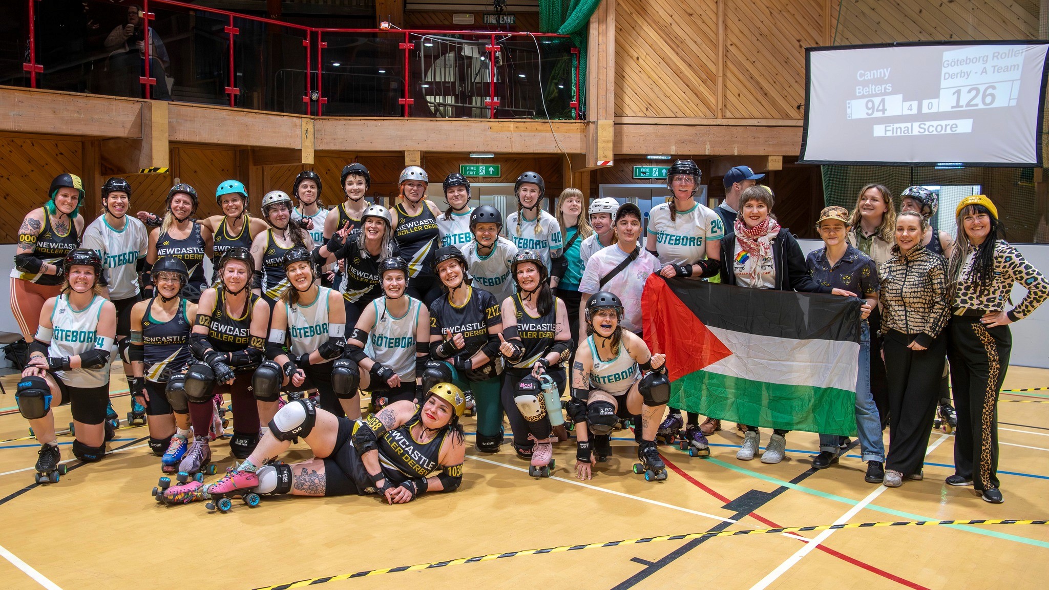 A group of roller derby standing in a circle, holding each others backs.