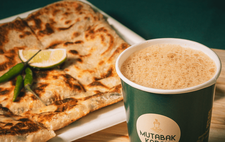 Barista pouring milk into striped ceramic mug