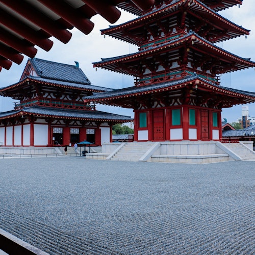 两座传统的日本塔楼，具有红白相间的细节，矗立在一个小石园旁。