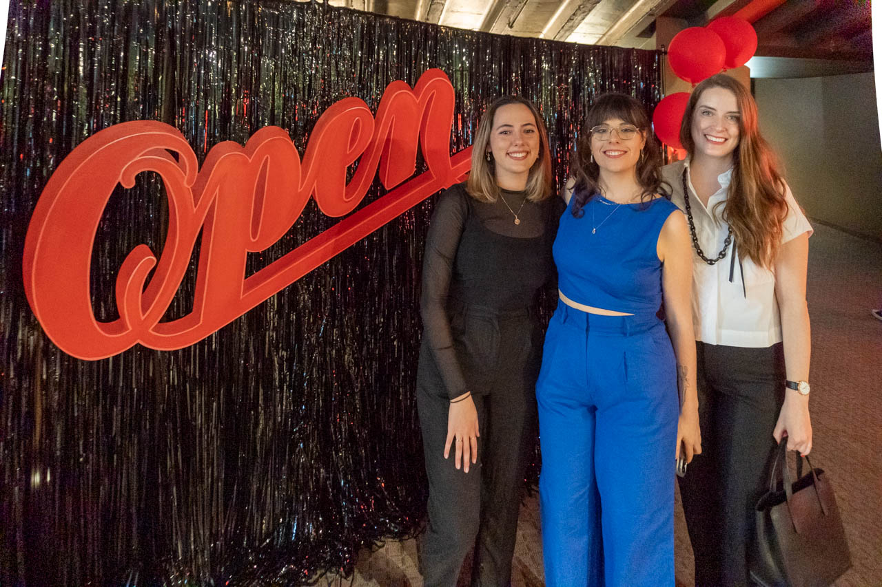three women standing at a in front of a sign