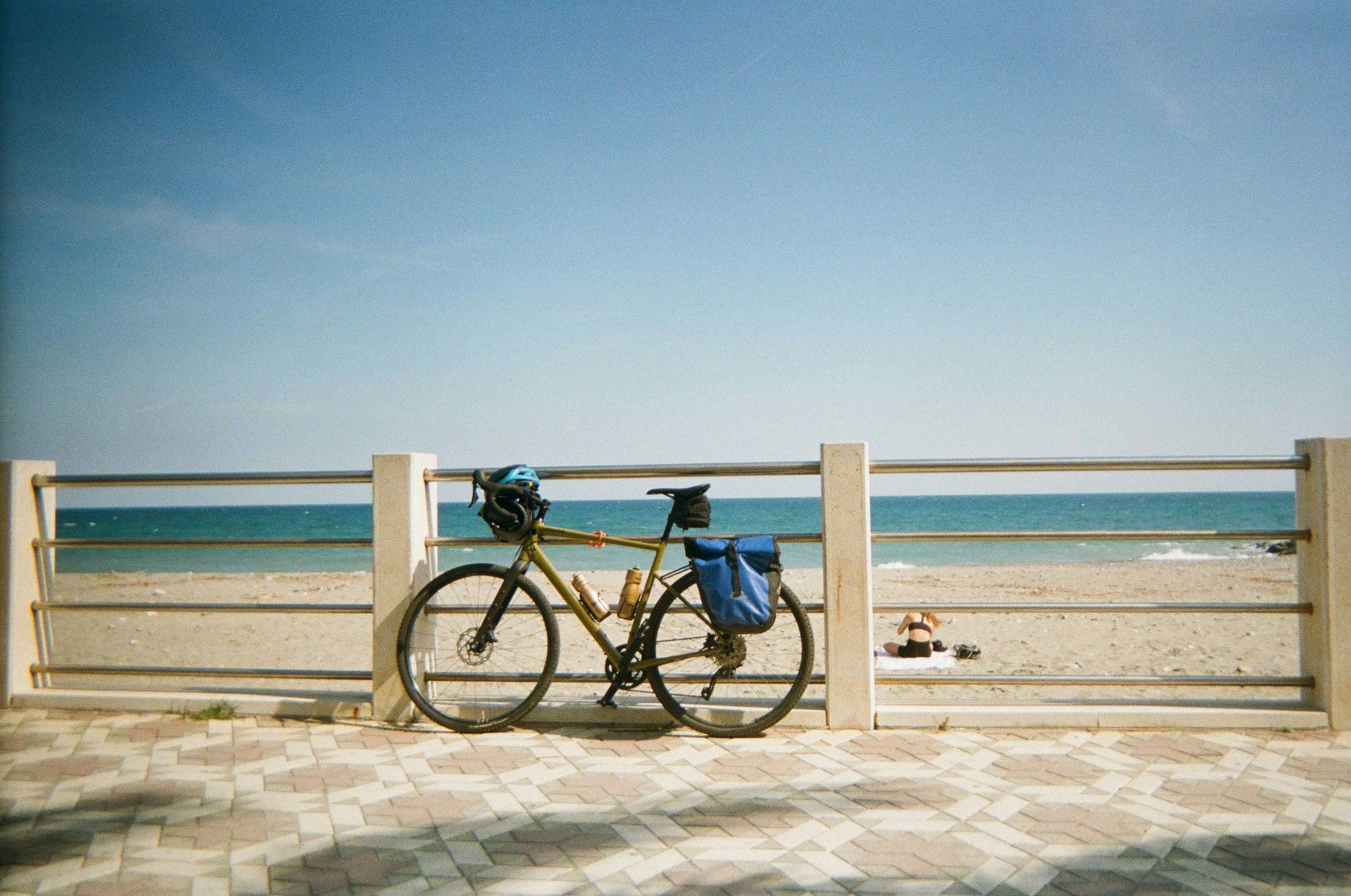 Bicycle parked by a beach railing under a clear sky