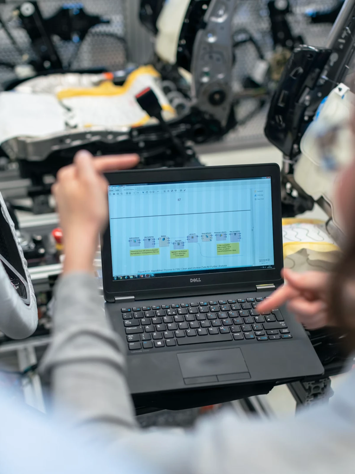 Laptop displaying data flow diagram in a factory setting.