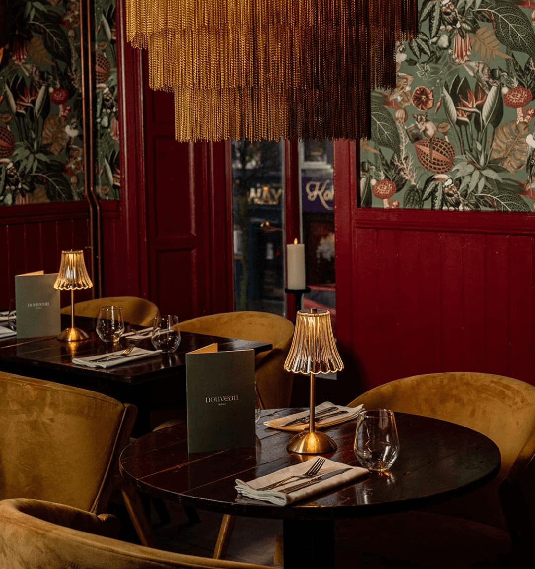Plate with a seared salmon fillet topped with green herb garnish and sauce, served on a white dish placed on a dark green marble table beside a white candlestick.