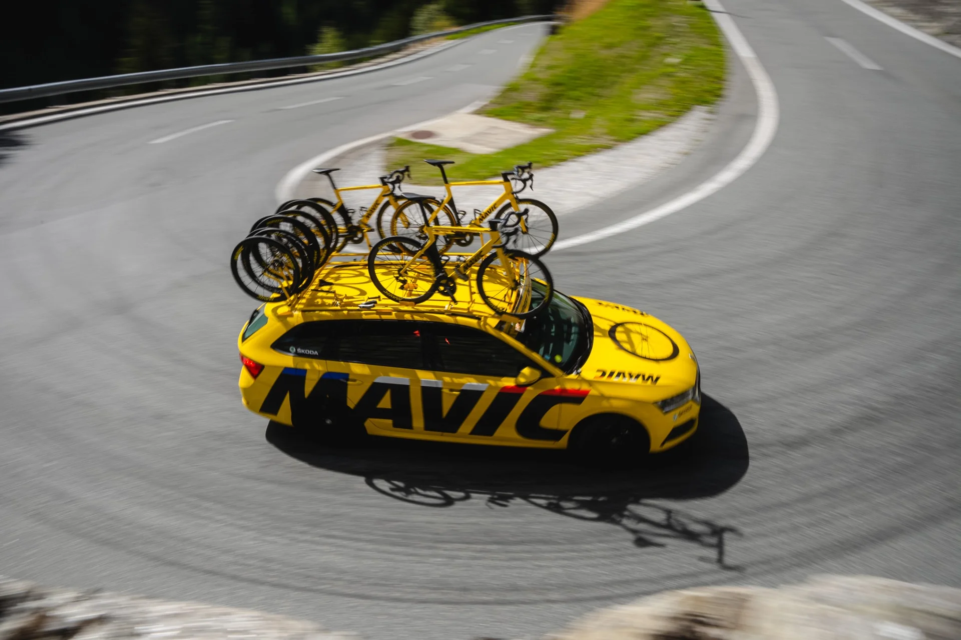 Mavic support car on mountain road with yellow bikes on roof - cycling race support
