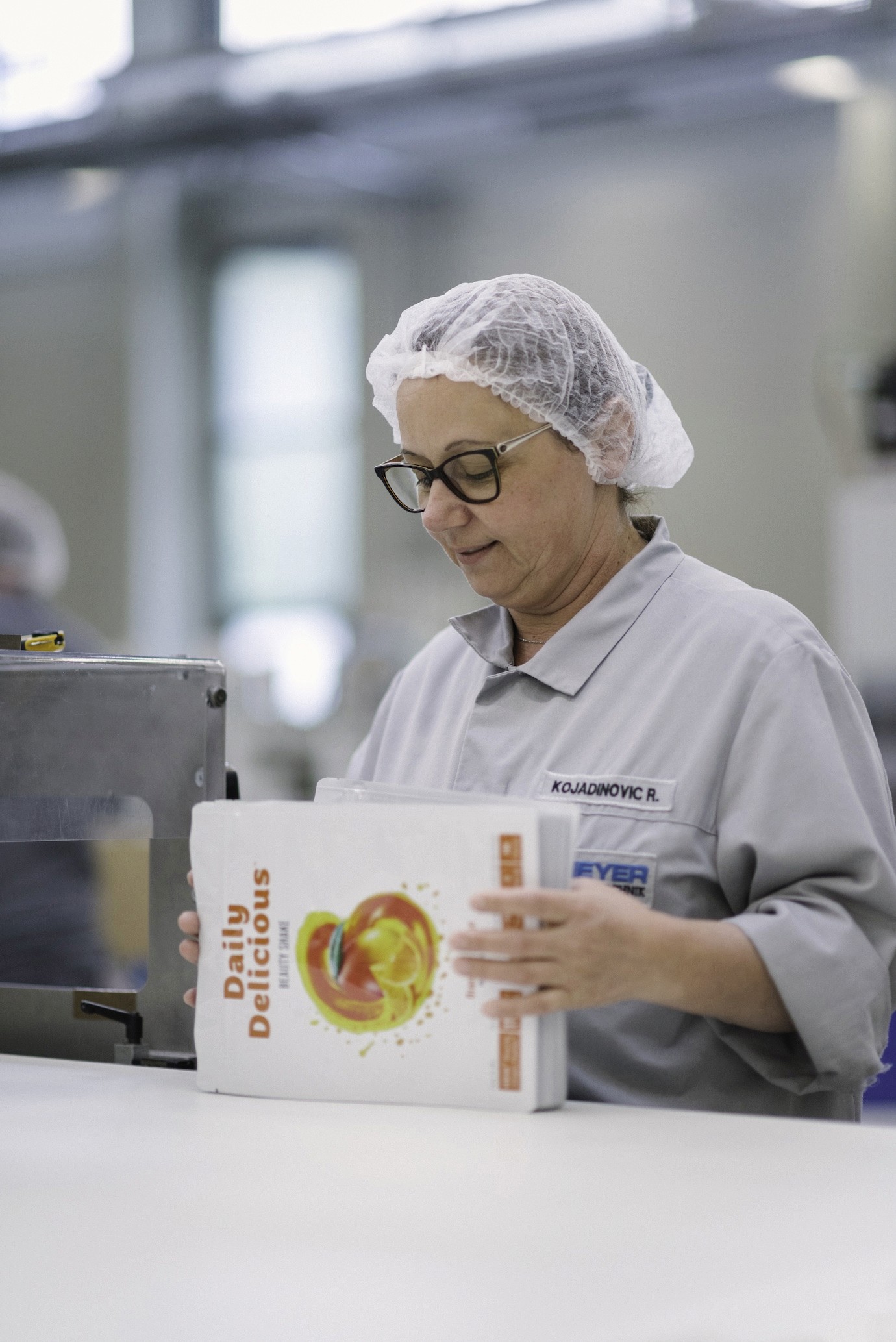 Scheyer-Mitarbeiter stapelt sorgfältig fertig verpackte Produkte und sorgt für Ausrichtung und Ordnung in der Produktionslinie.