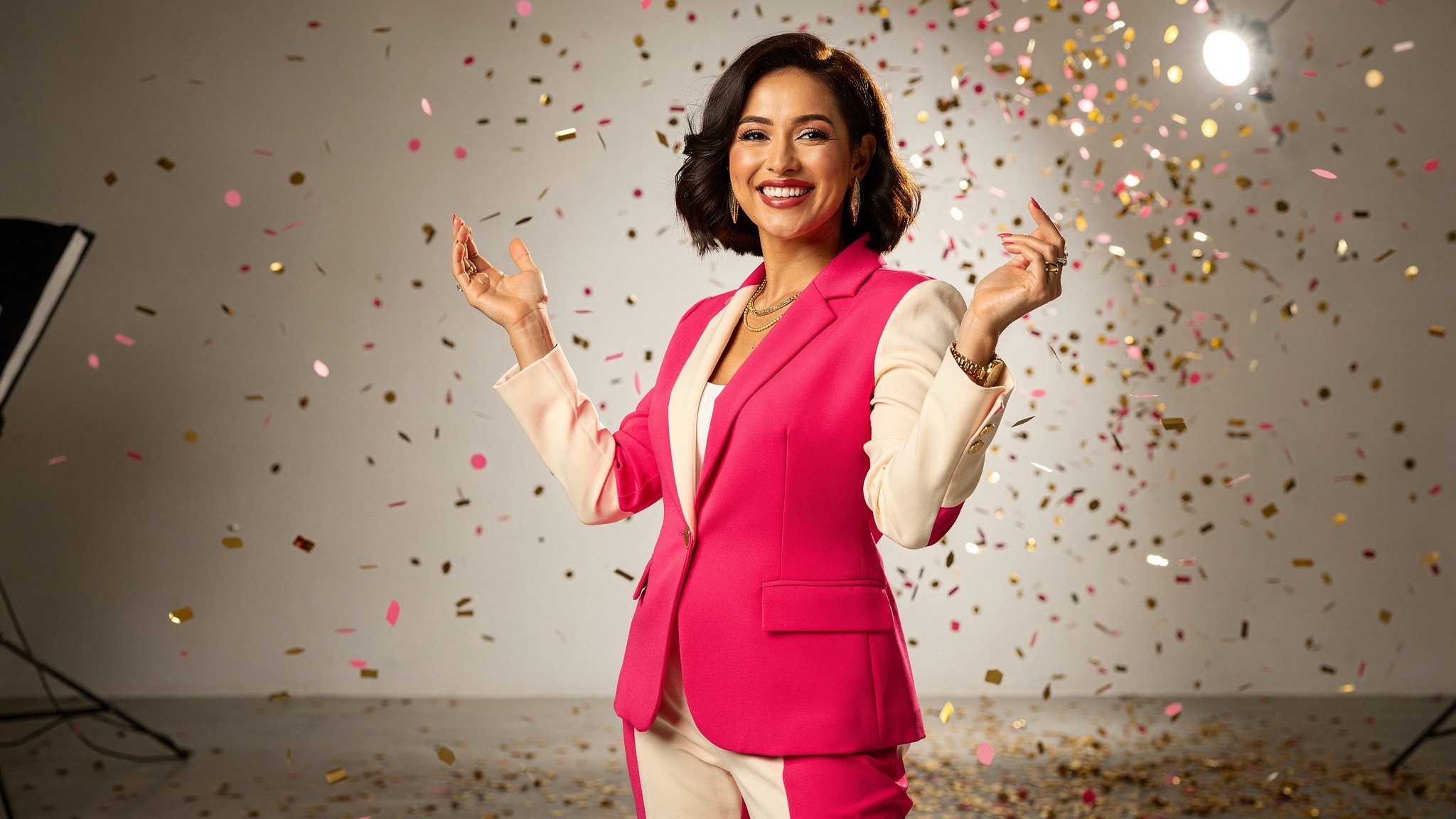 Creator celebrating with a genuine bright smile and arms raised, soft confetti around her
