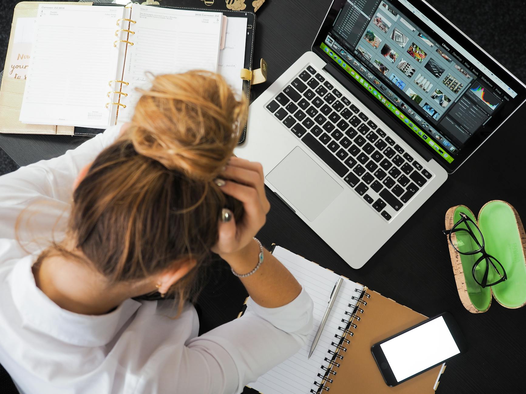 Close-up of a frustrated person staring at a laptop screen with several tangled charging cables on a messy desk.