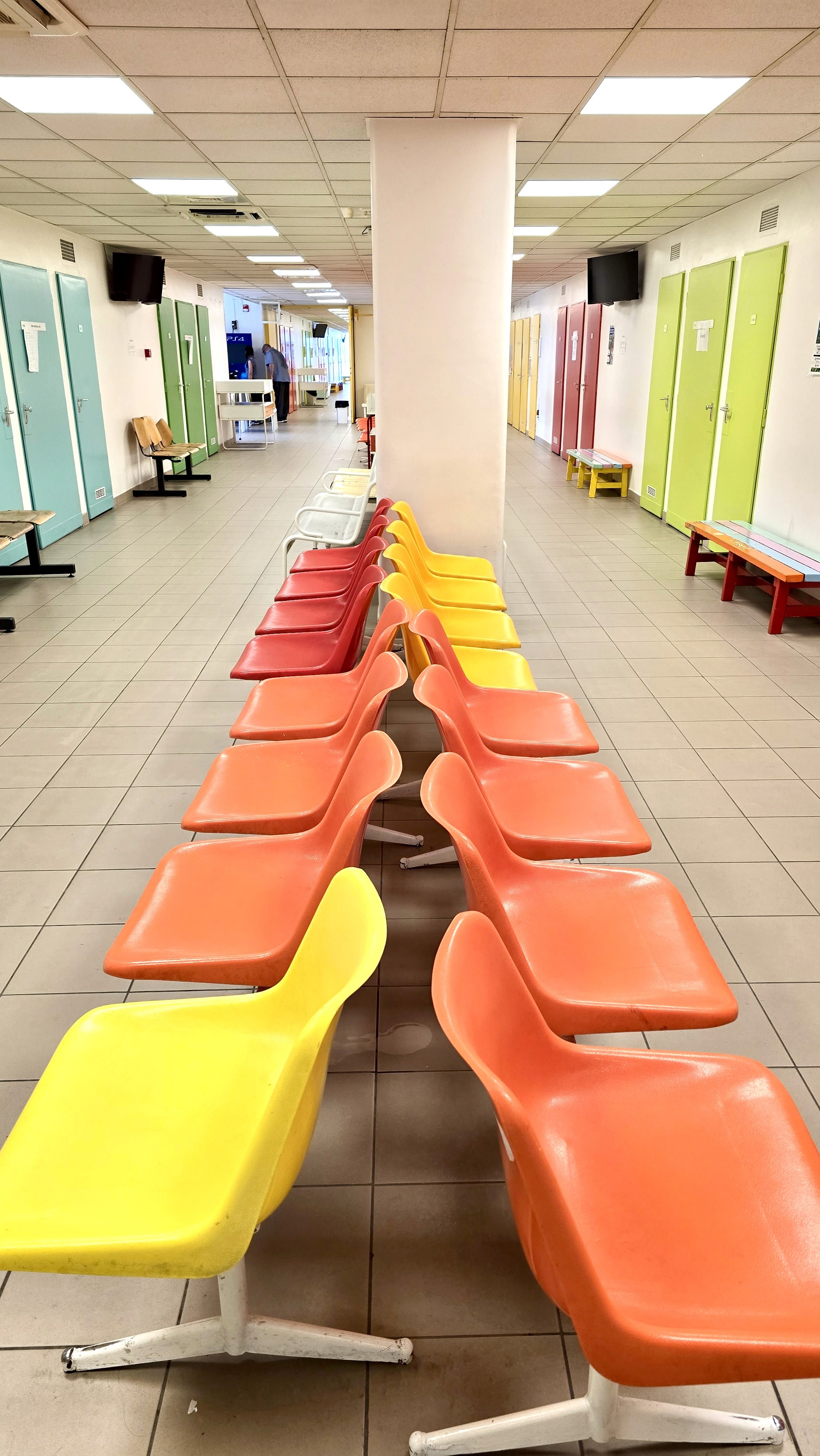 FElvételi iroda folyosója színes műanyag széksorokkal.