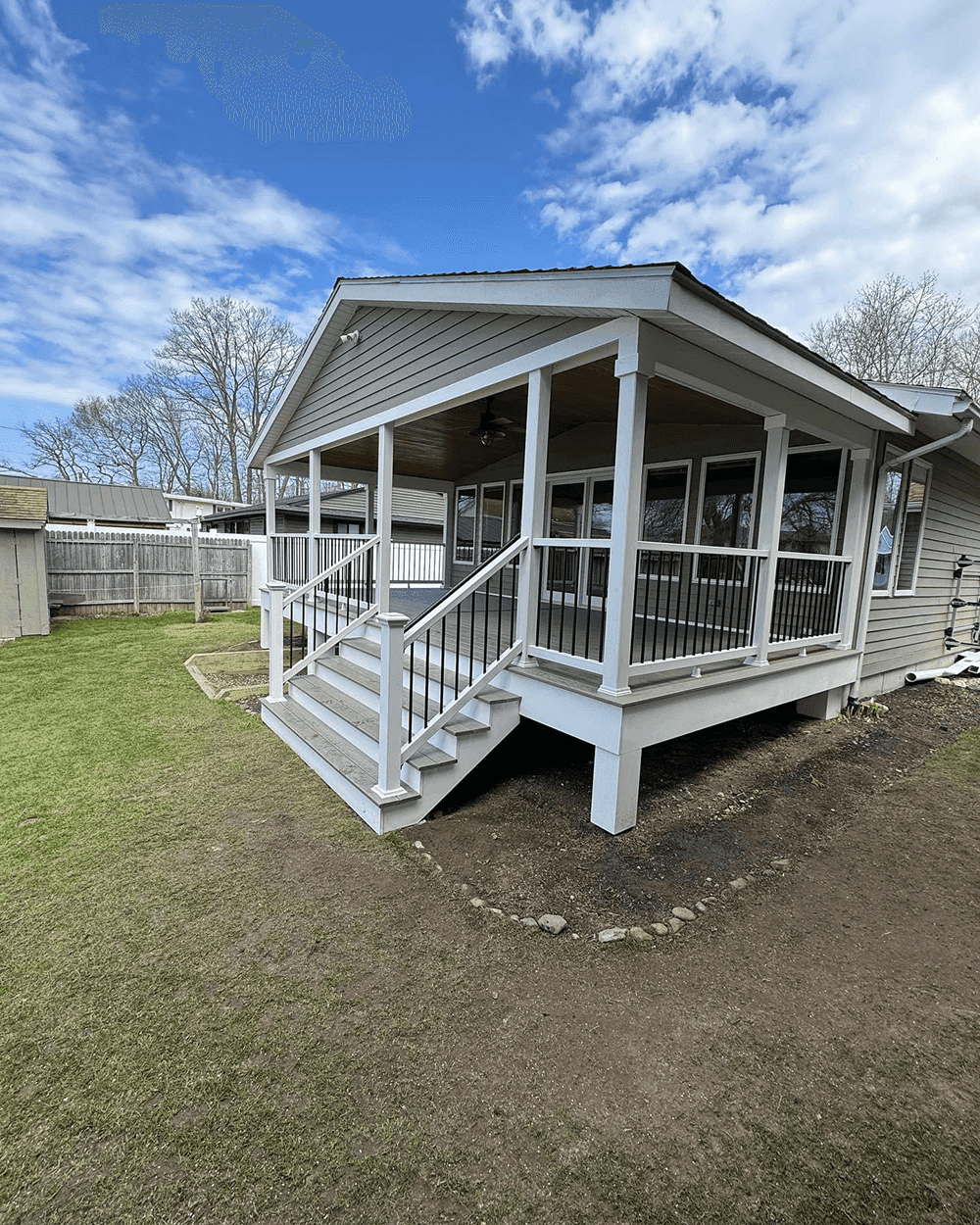 Grey Trex deck with white railings looking out at a lake with a dock