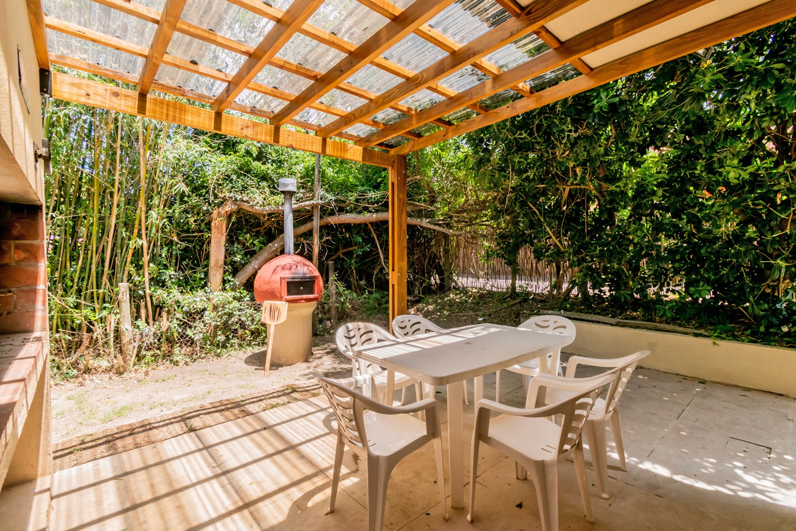 Parrillero y mesa techada en patio trasero de Casa Albatros - espacio al aire libre con techado, perfecto para disfrutar en familia.