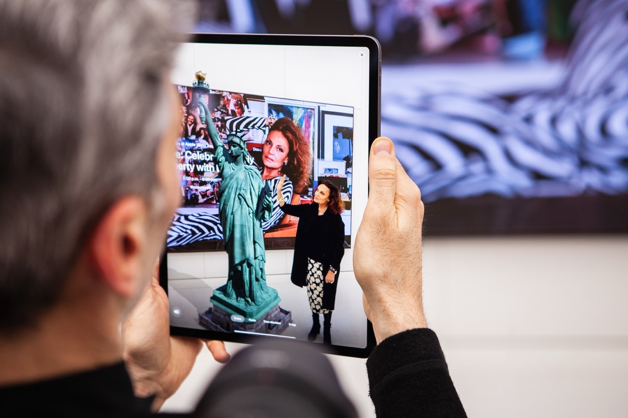 Attendee holding an iPad during an event demo, showing an on-screen experience in a live presentation setting.
