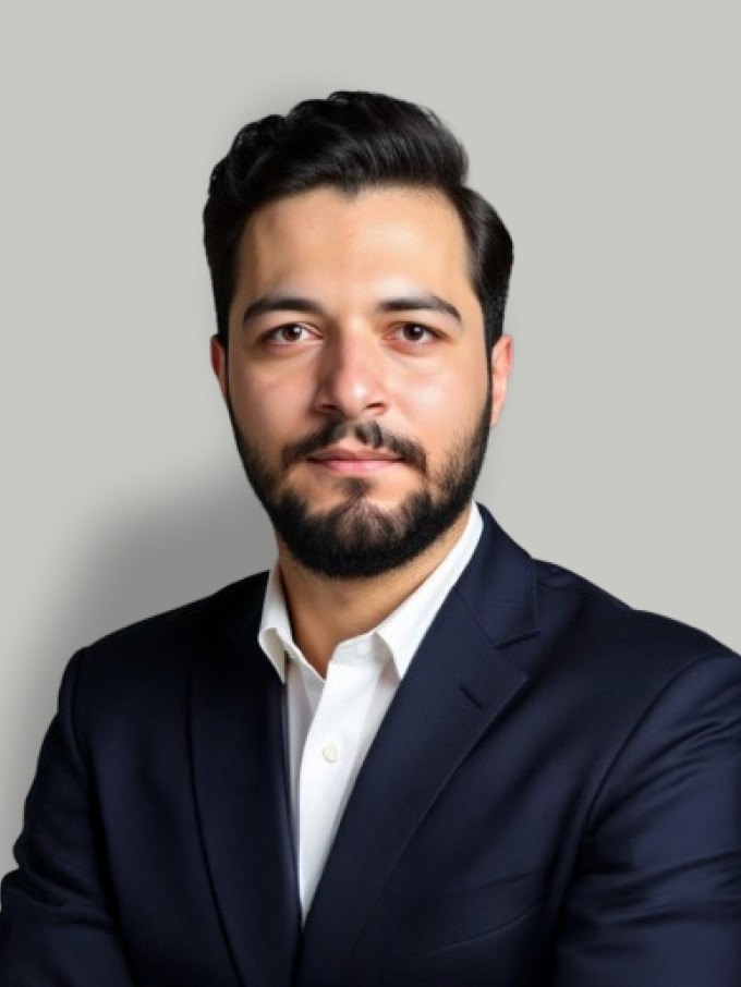 A young man in a white t-shirt stands against a light-colored background.