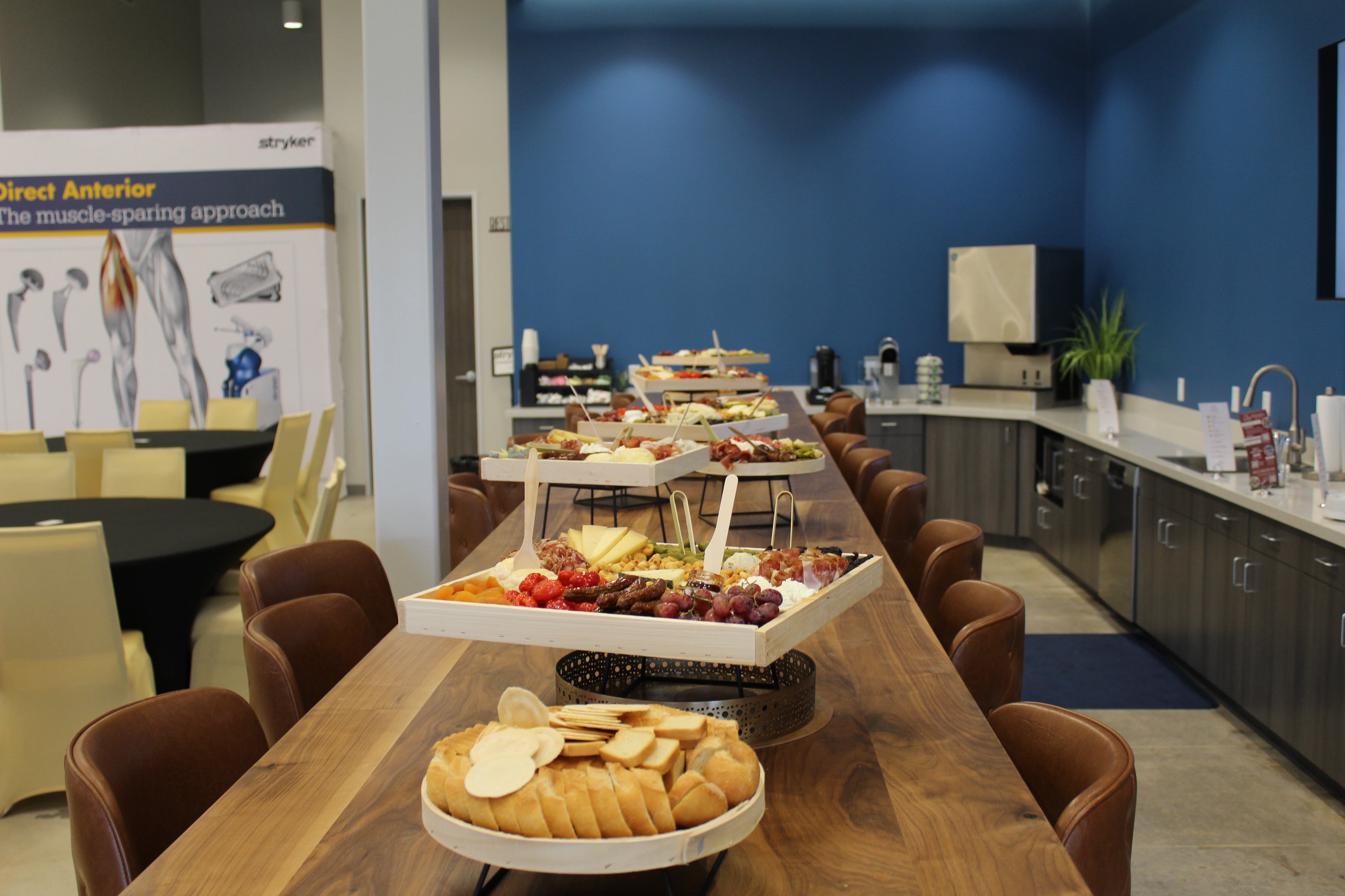 A young person with curly hair smiles at the camera while sitting in front of a laptop against a dark background.
