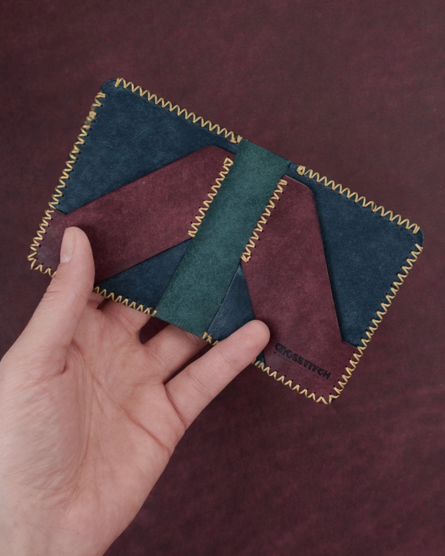 Handcrafted leather bifold wallet by Crosstitch Leather in tan and olive tones with yellow hand stitching.