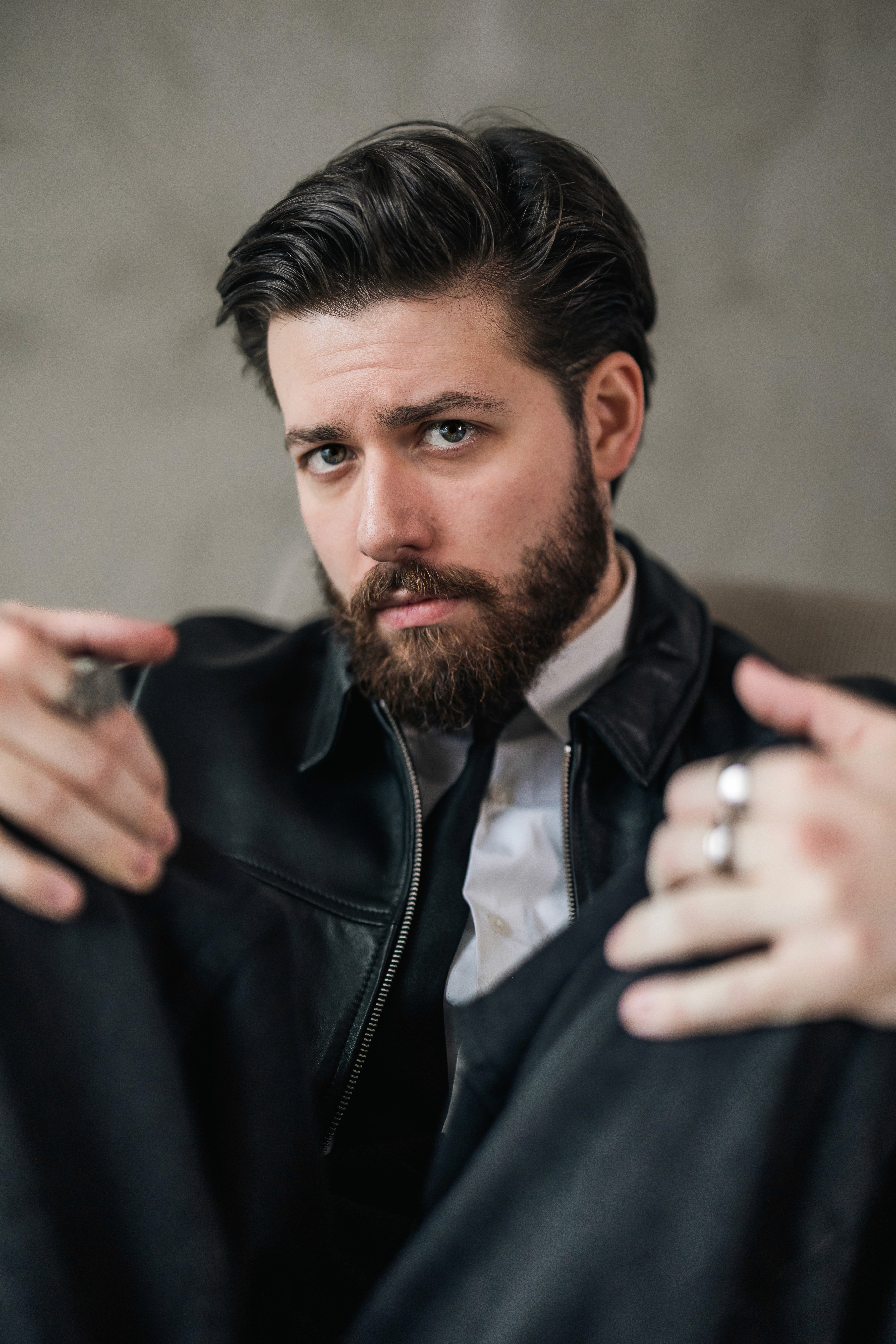 Férfi ül keresztbe tett lábbal fekete-fehér stúdióportrén, farmerben és pólóban, klasszikus hangulatban.​