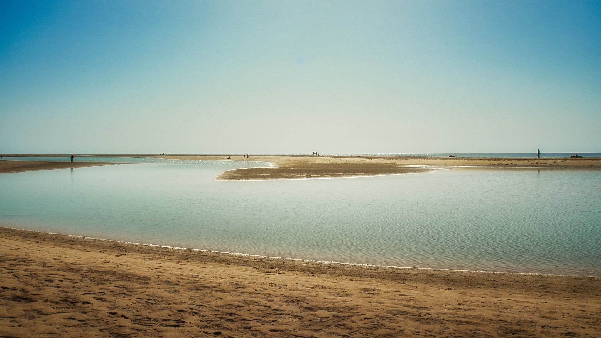 Strand, Meer, blauer Himmel, wenige Siluetten von Menschen
