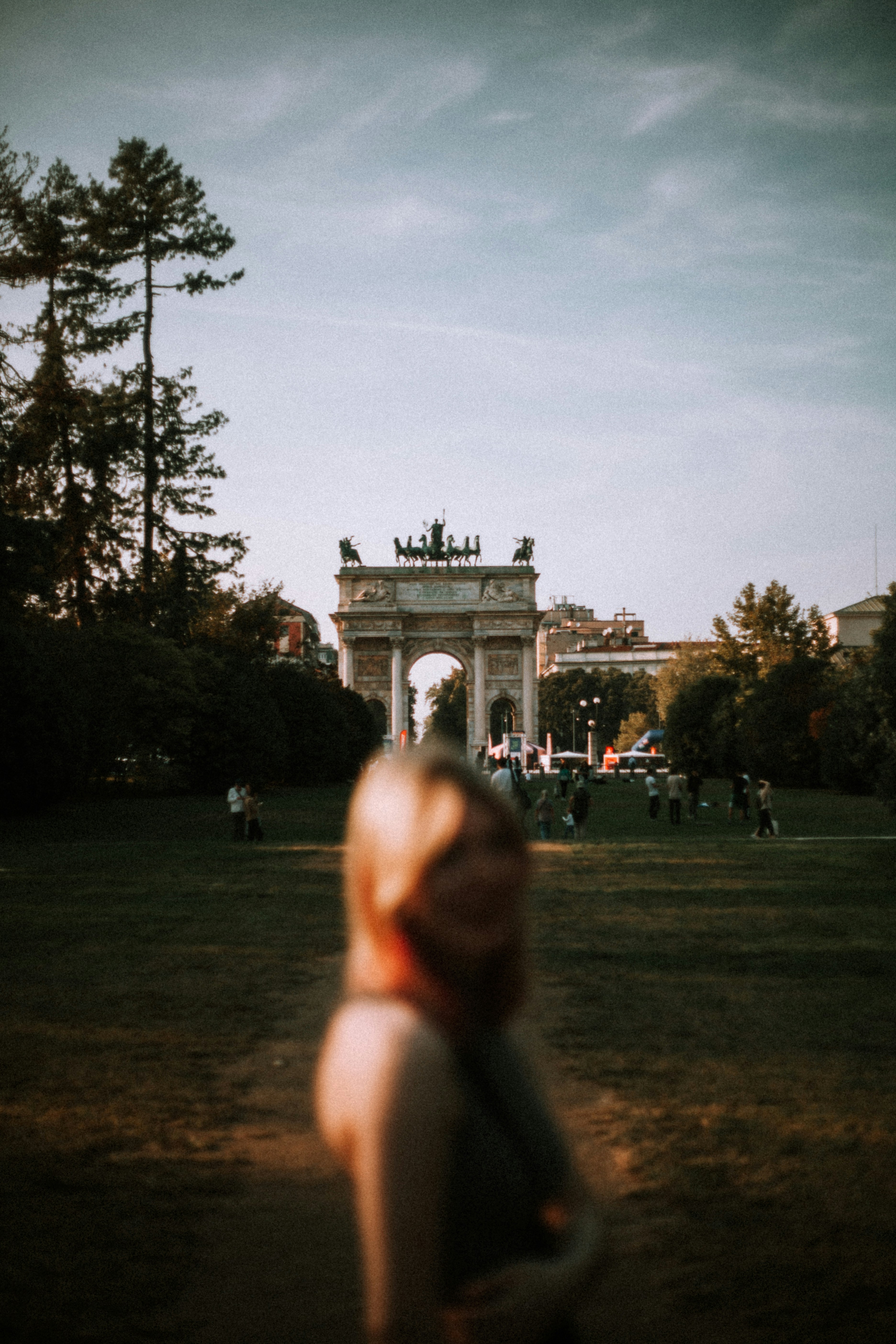 a person standing in a grass field with a large stone structure in the background
