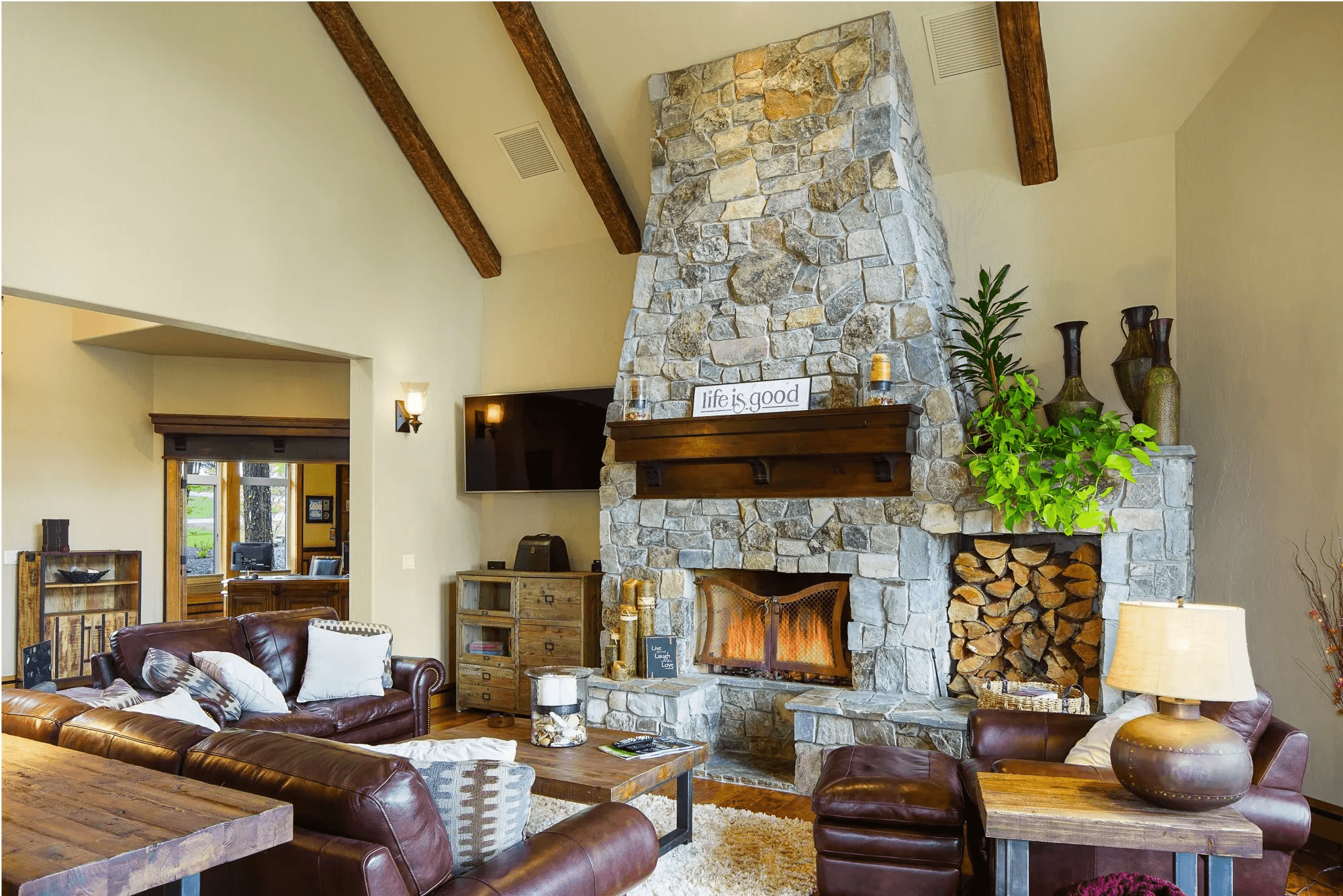 Leather sofas facing a stone fireplace with a tv