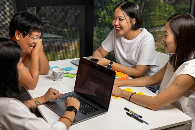 An image of a few 55 Minutes' members having a discussion around the table at the office.