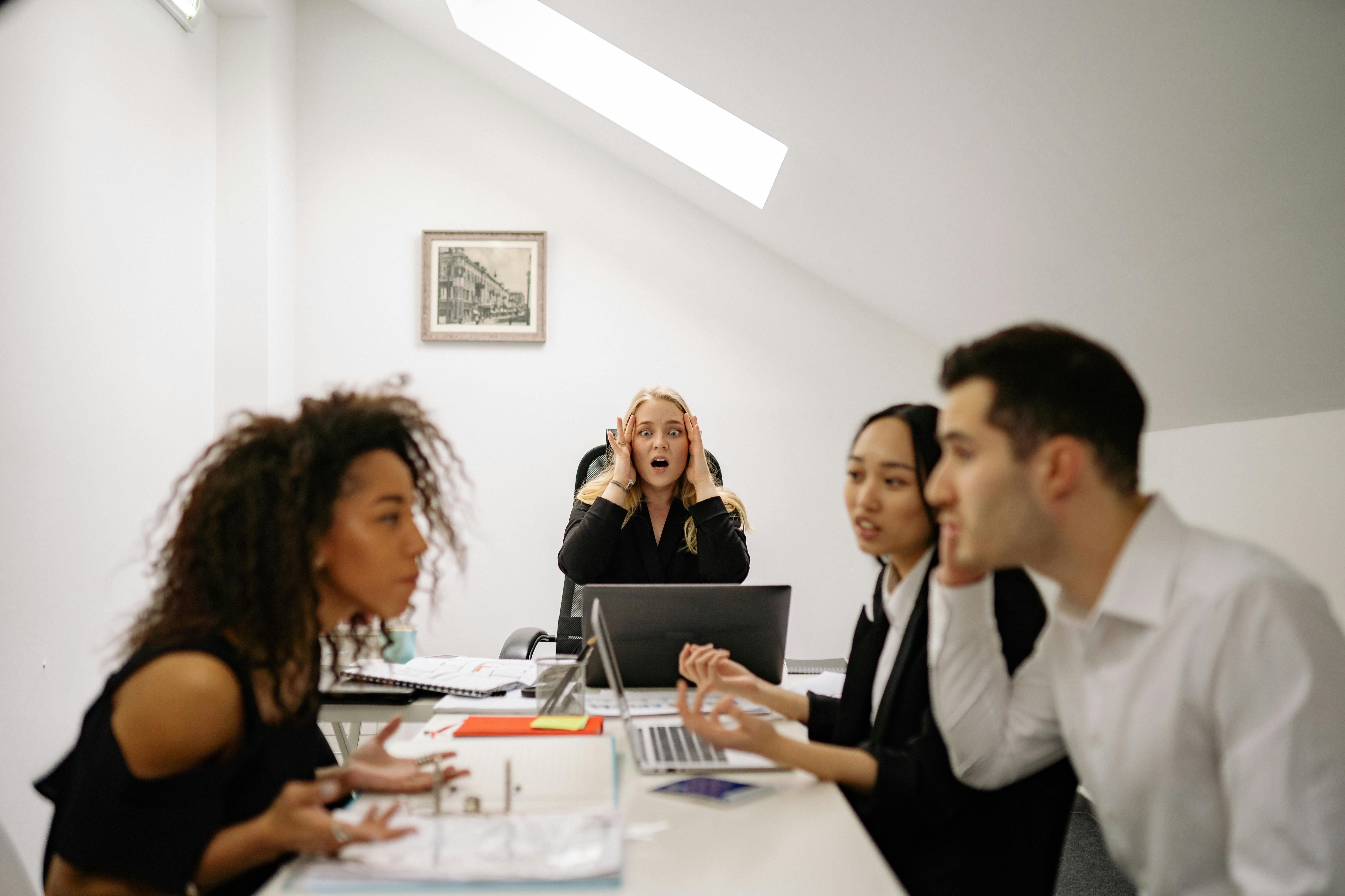 Team in ufficio durante una riunione caotica con persone frustrate e confuse, metafora della perdita di motivazione e del senso di disorientamento nel mercato del lavoro del 2026.
