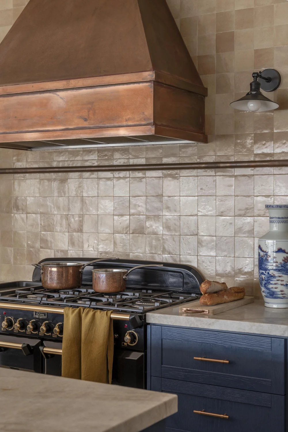 Kitchen sink with brushed brass tap, stone benchtop, and textured tiled splashback.